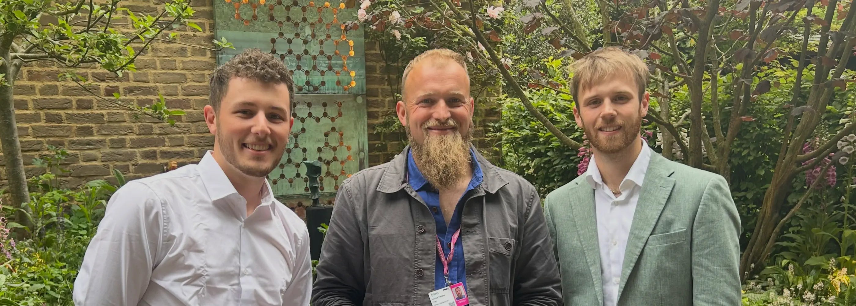 Three men standing in front of a garden at Chelsea Flower Show with Silver Guilt medal