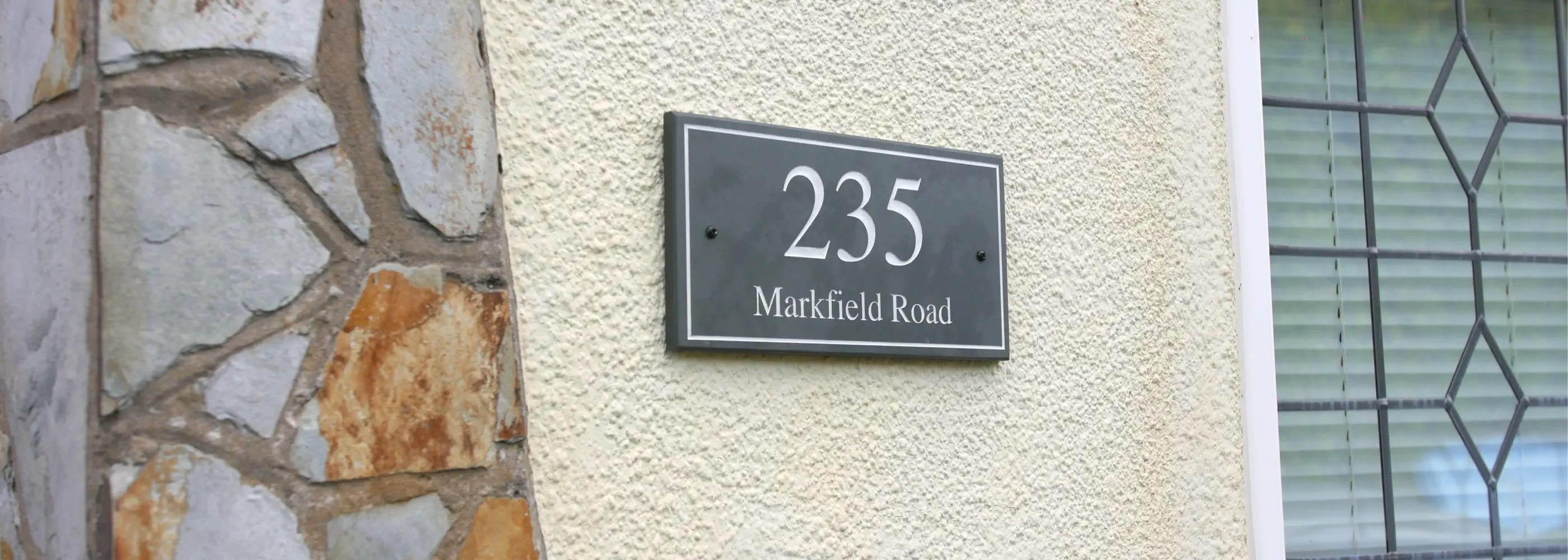 Slate house number sign '235' on a stone wall