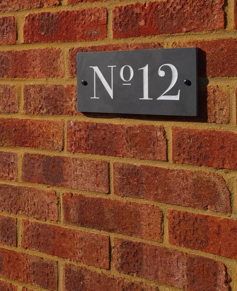 House number plaque 'No. 12' on a brick wall
