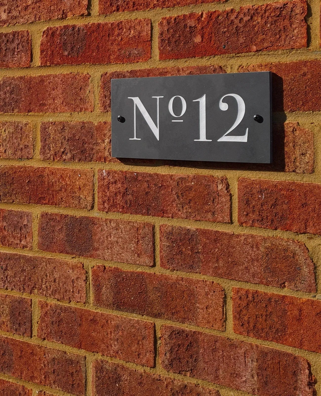 House number plaque 'No. 12' on a brick wall