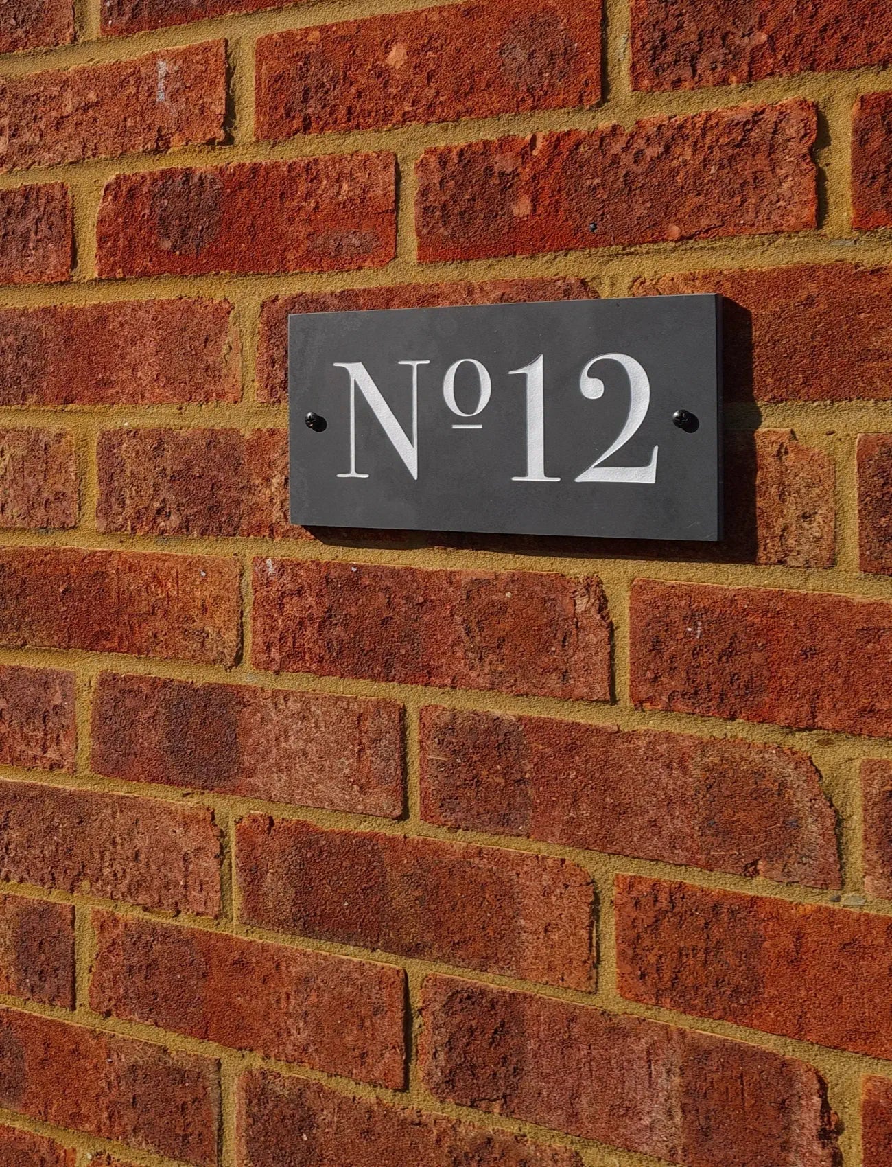 House number plaque 'No. 12' on a brick wall
