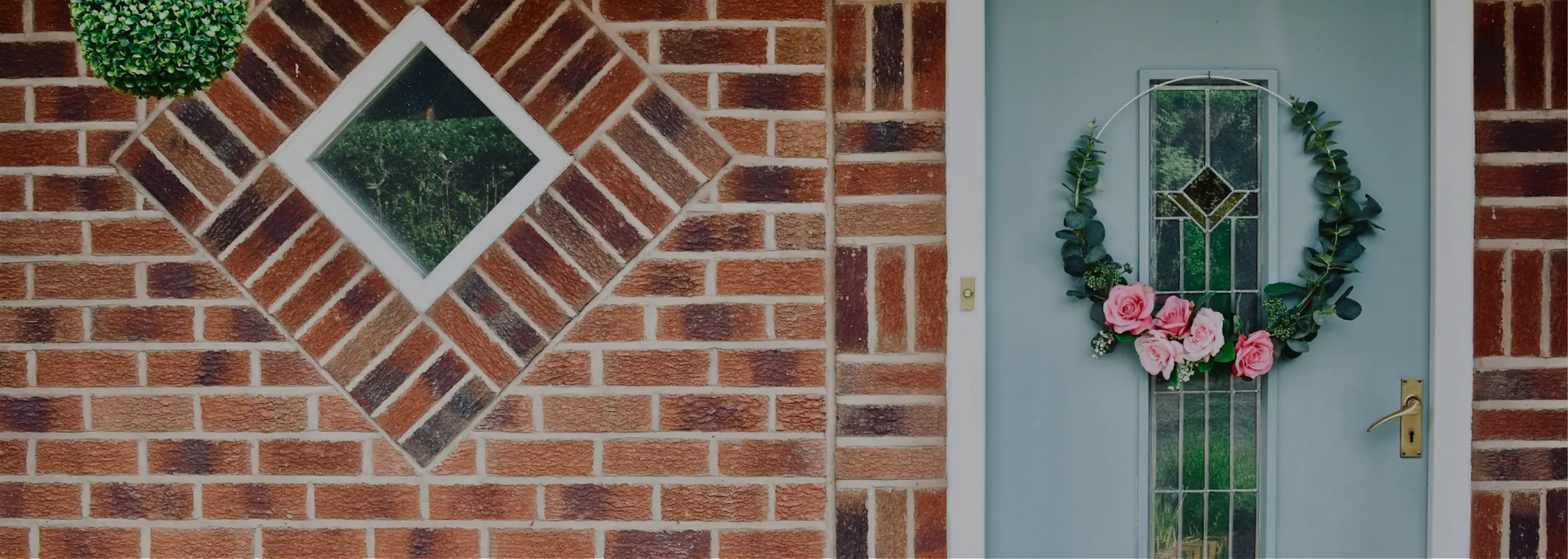 Brick wall with decorative diamond pattern and a door with floral wreath.