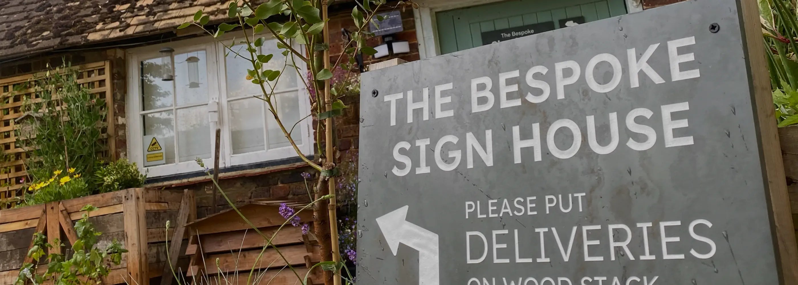 Sign for 'The Bespoke Sign House' with the workshop in the background