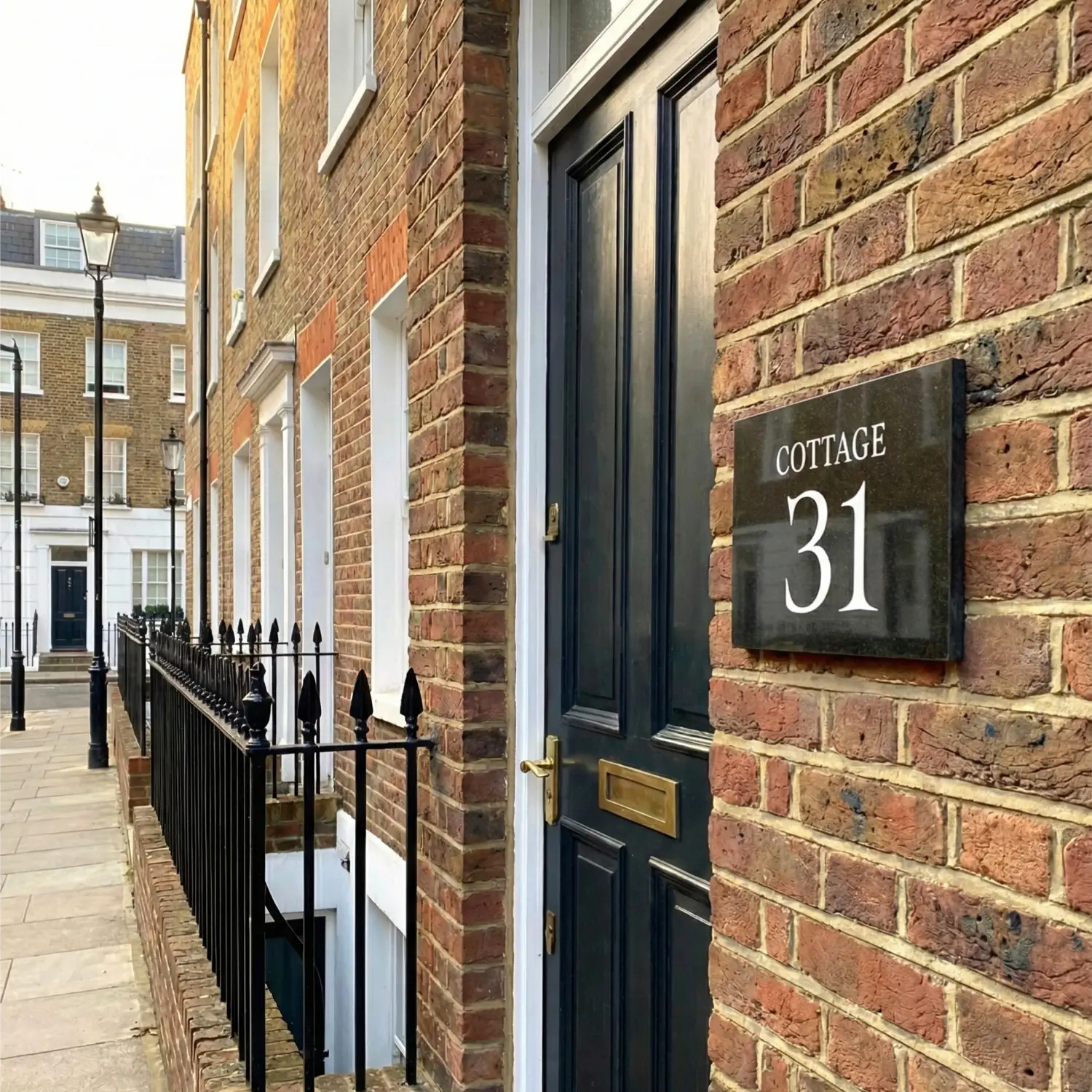 Brick building with a black door and house number sign 'Cottage 31'.