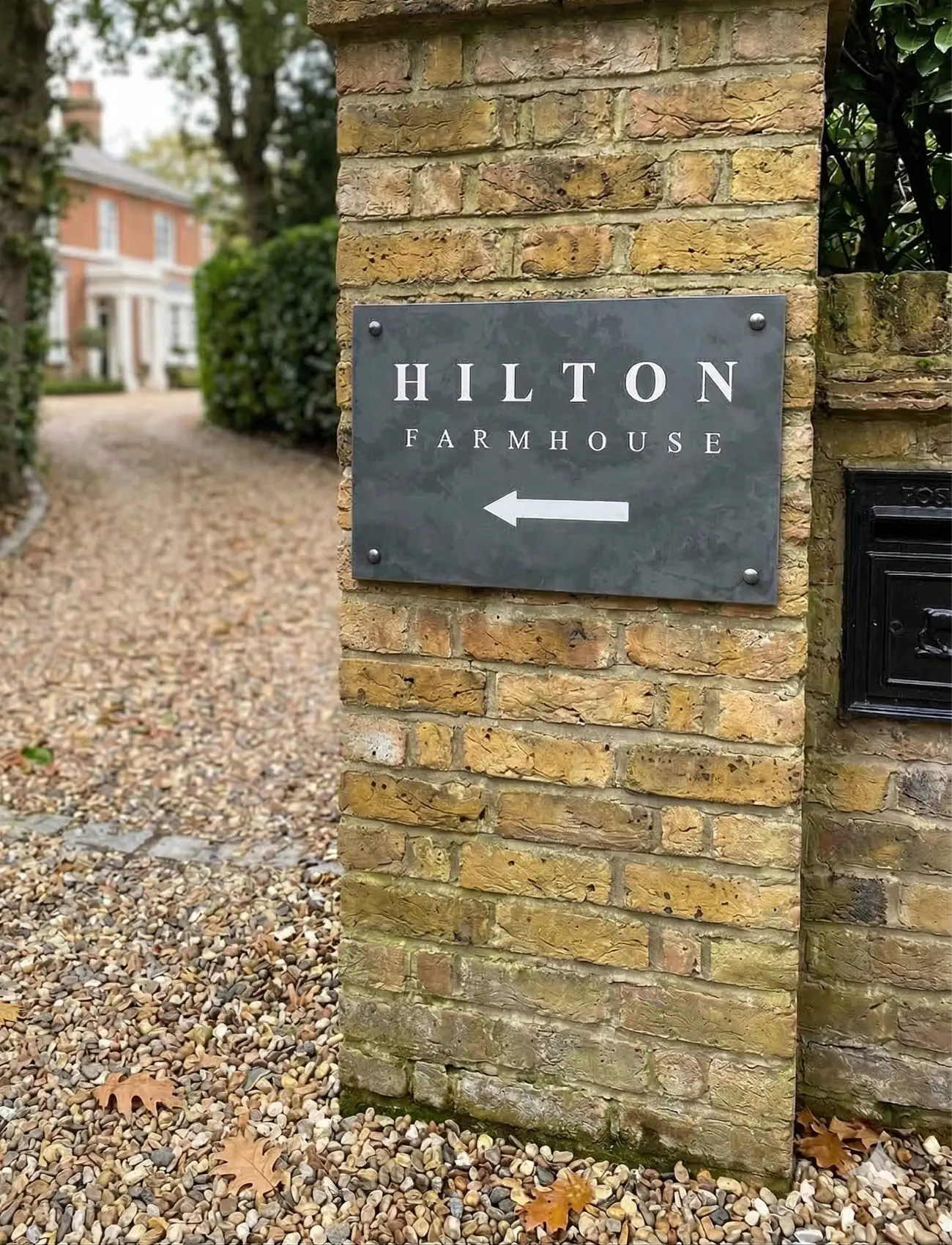 Brick wall with a sign pointing to 'Hilton Farmhouse'