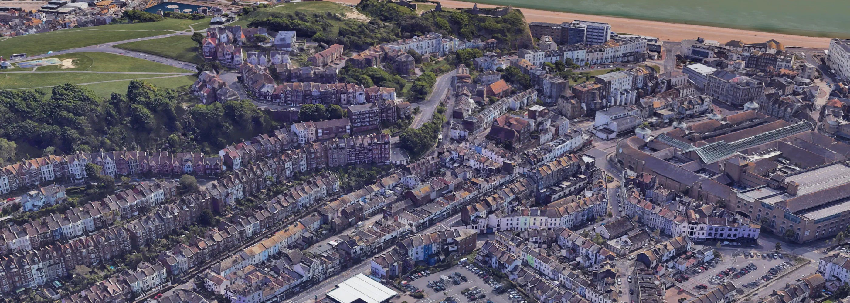 Aerial view of a coastal town with buildings and greenery.
