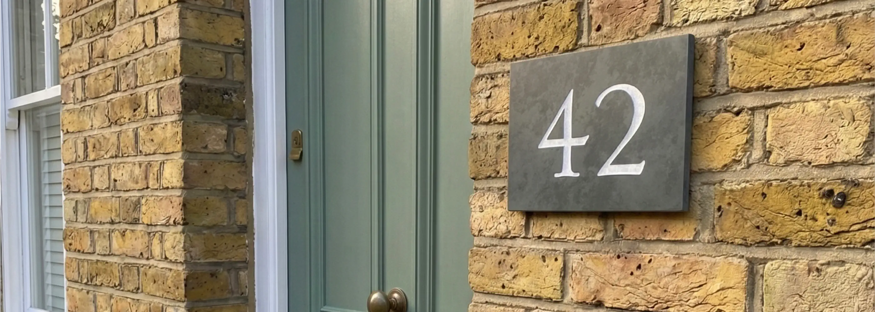 House number sign with '55 Cattle Dyke' on a brick wall