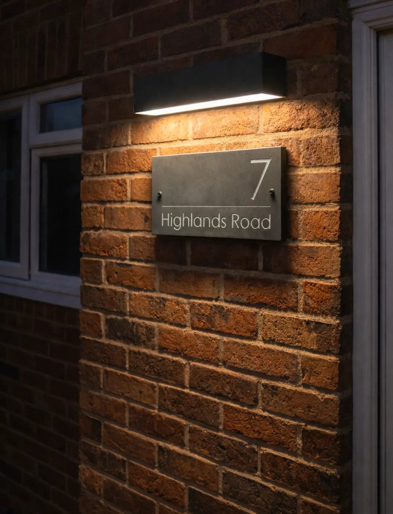 House number sign on a brick wall with a light fixture above