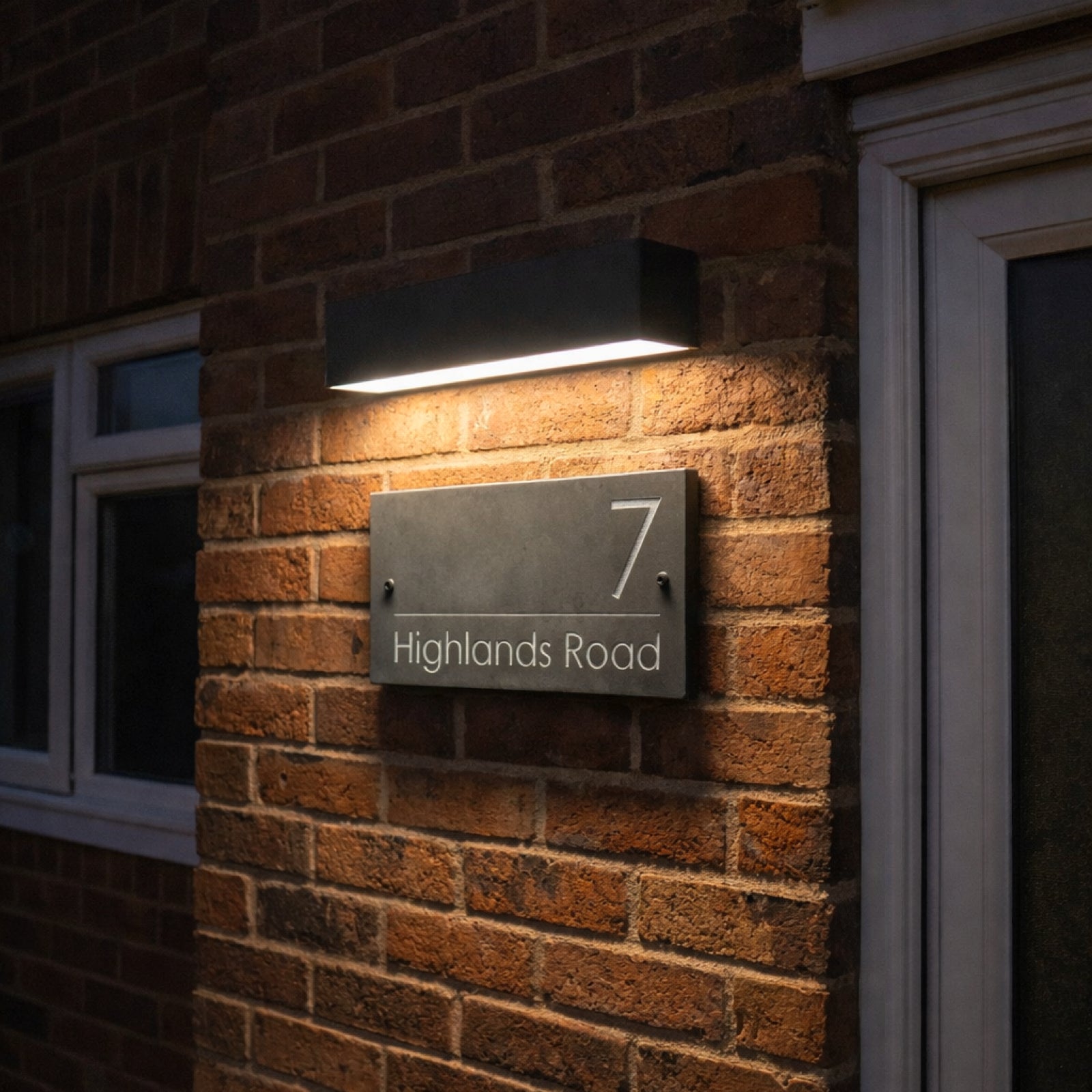 House number 7 sign on a brick wall with a light fixture above.