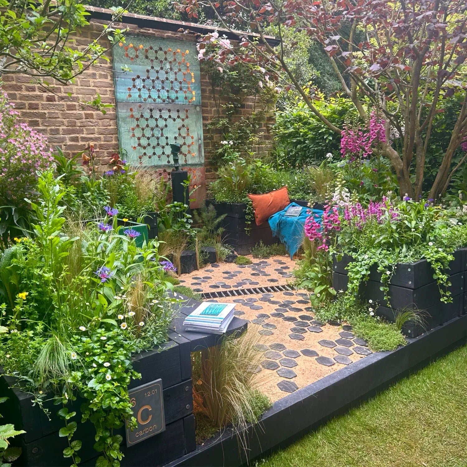 Garden with plants, a bench, and a colorful wall art piece.