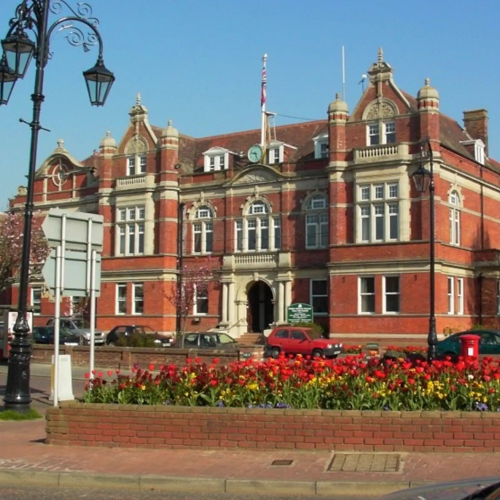 Red brick building with floral garden in front on a clear day