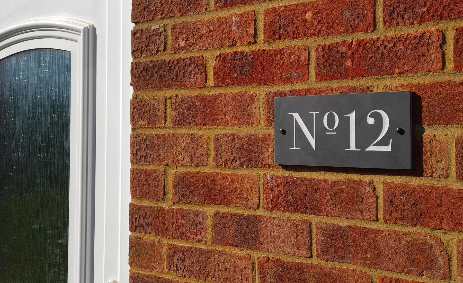 House number 'No. 12' on a brick wall next to a door
