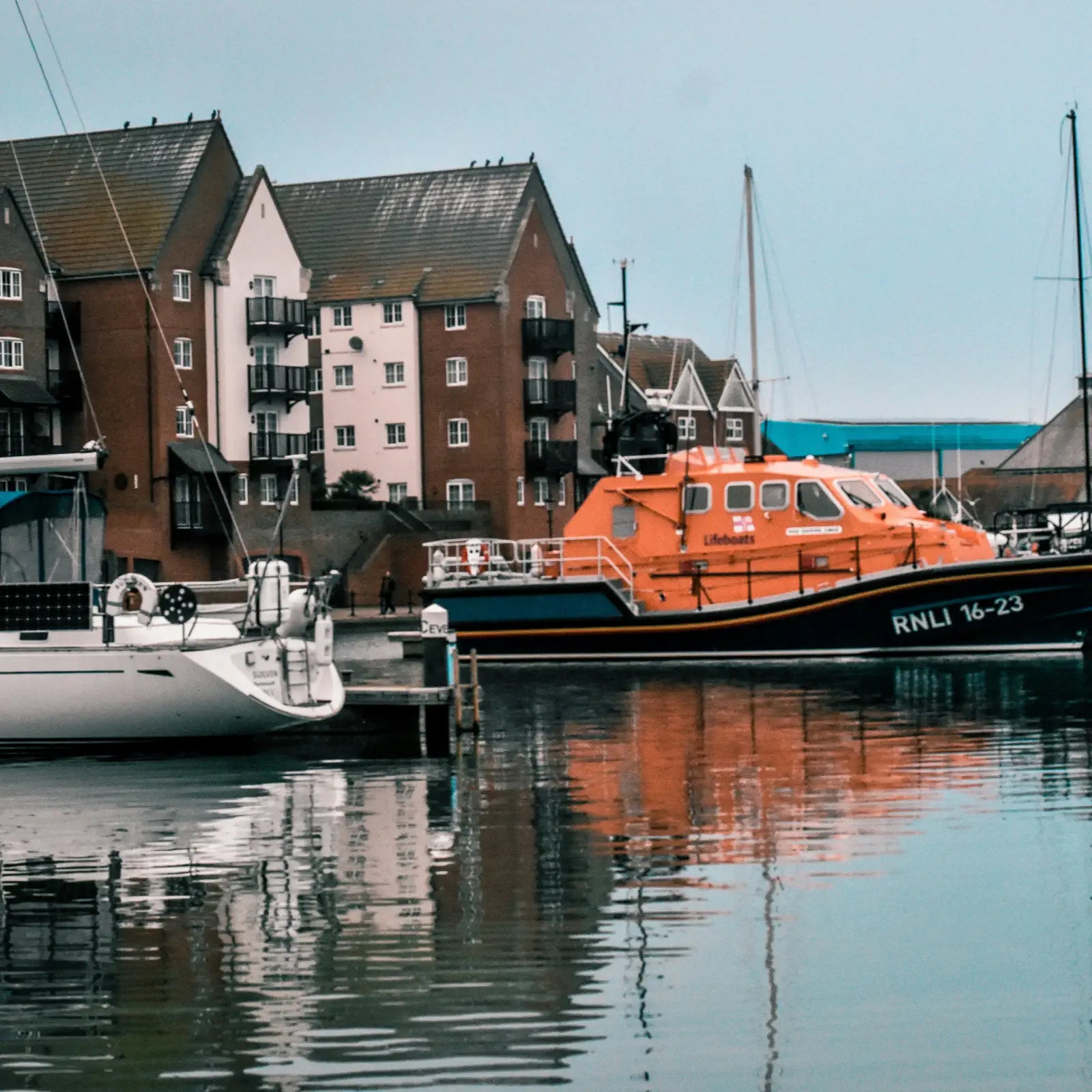 Orange lifeboat docked at a harbor with residential buildings in the background