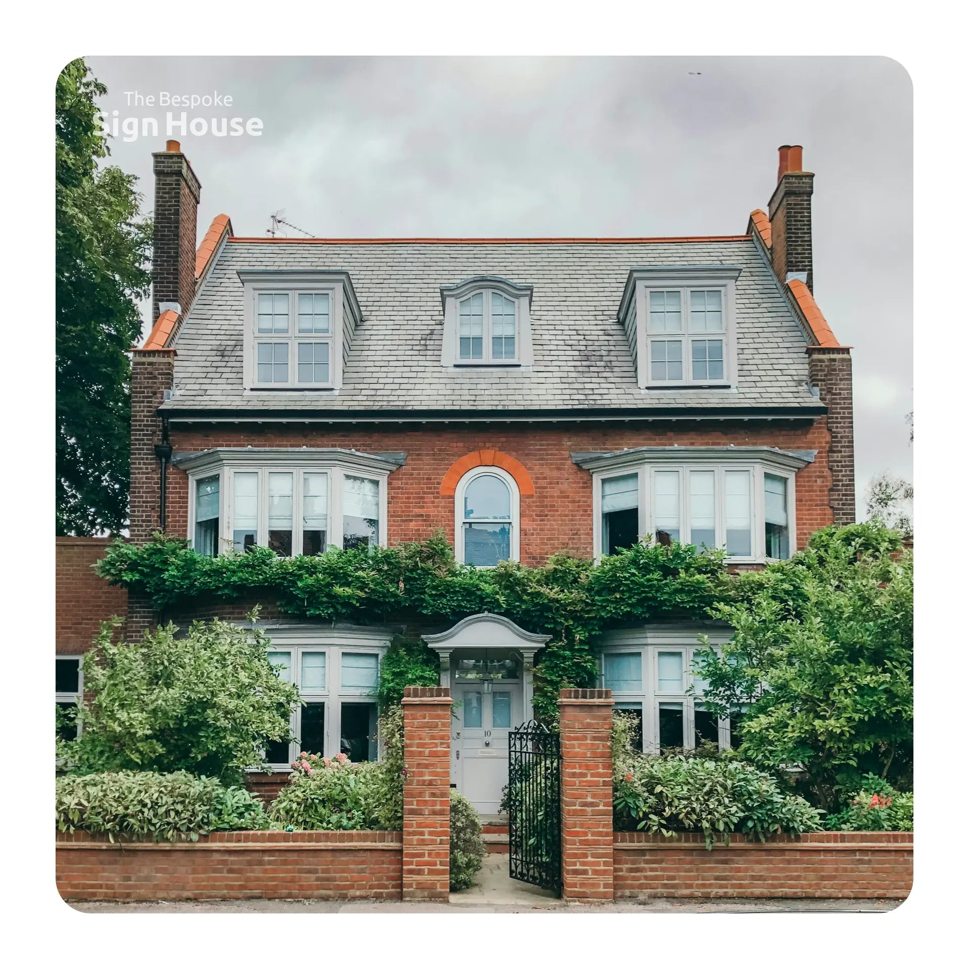 Two-story brick house with greenery in front on a cloudy day