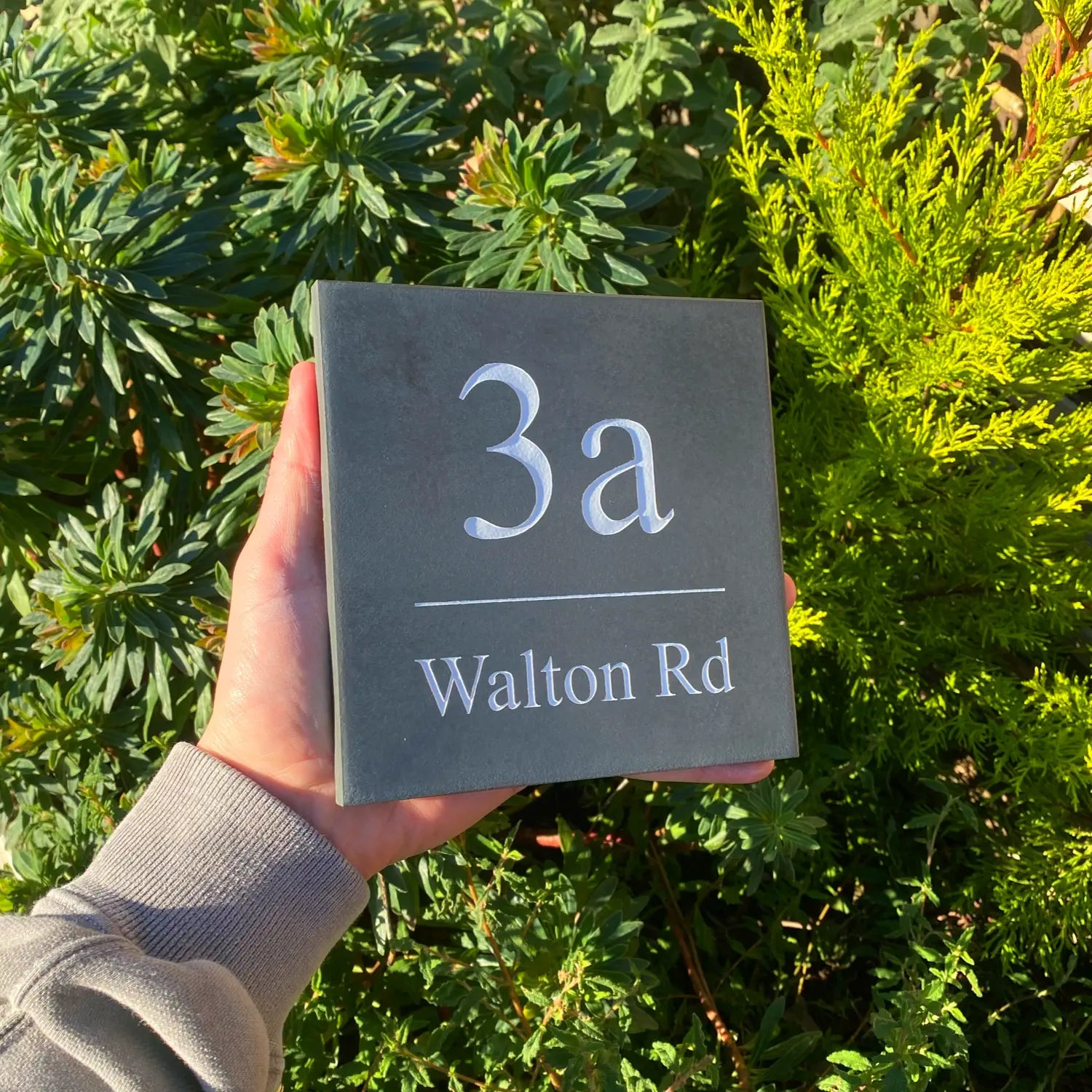 a simple slate house sign with the house number and street name engraved into the surface and painted white
