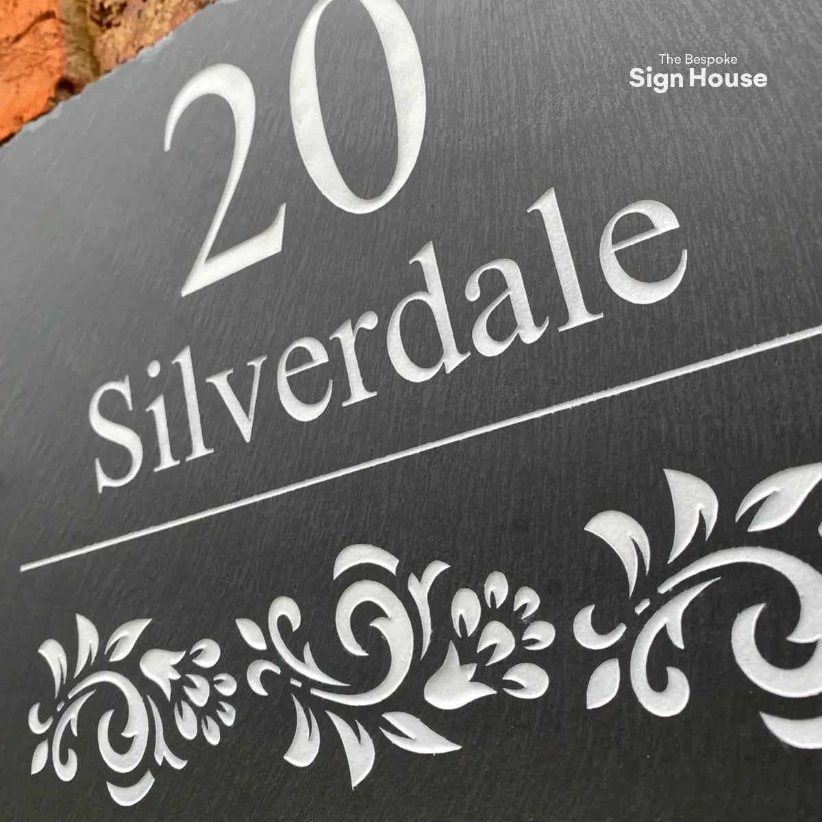a slate house sign with road name and number