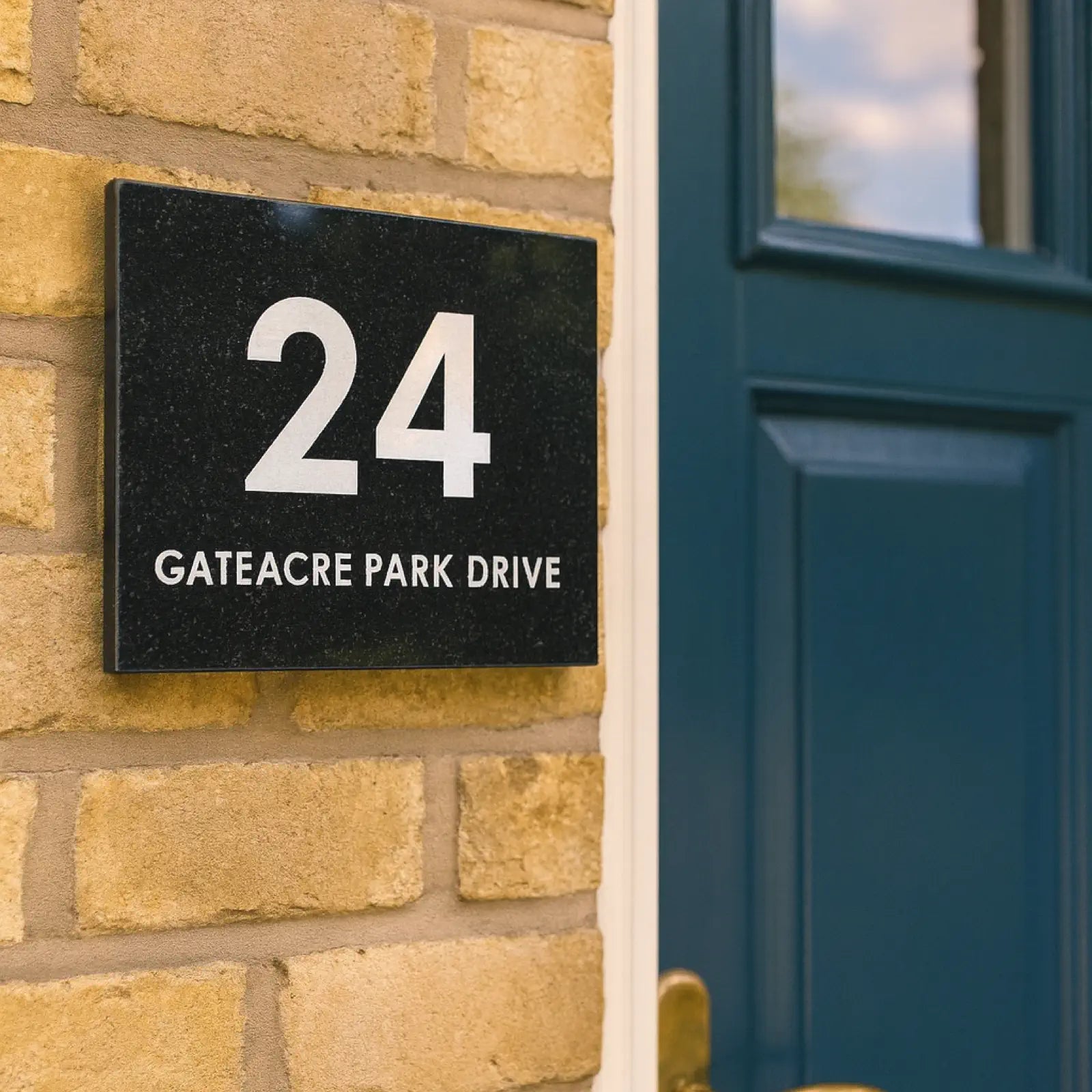 Granite house number sign on a brick wall with '15 Barton Wood Road' text