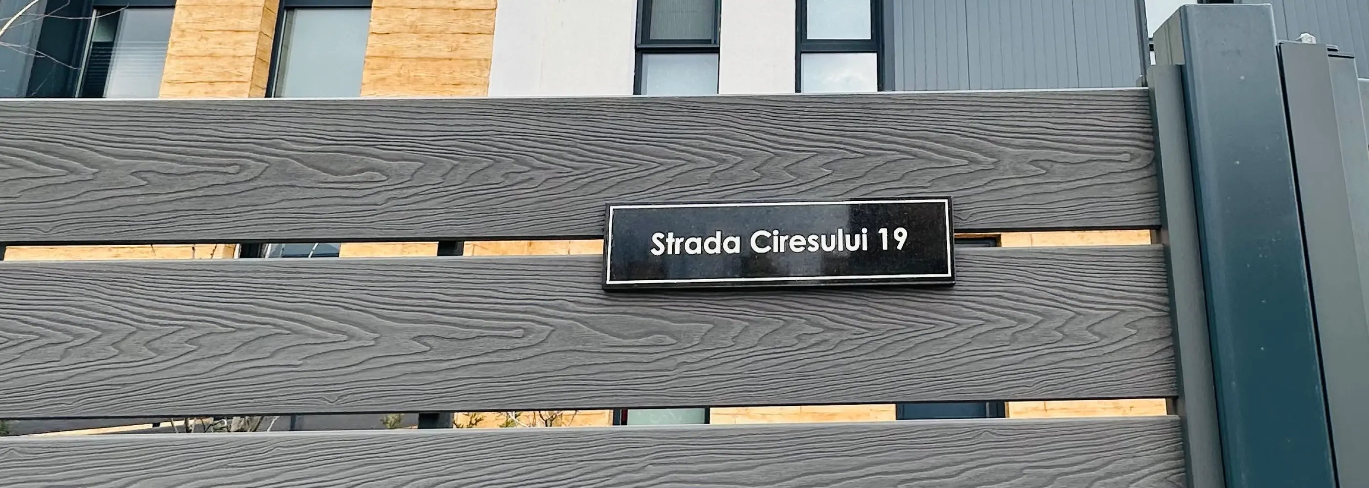 Metallic gate with a sign reading 'Strada Ciresului 19' in an urban setting.