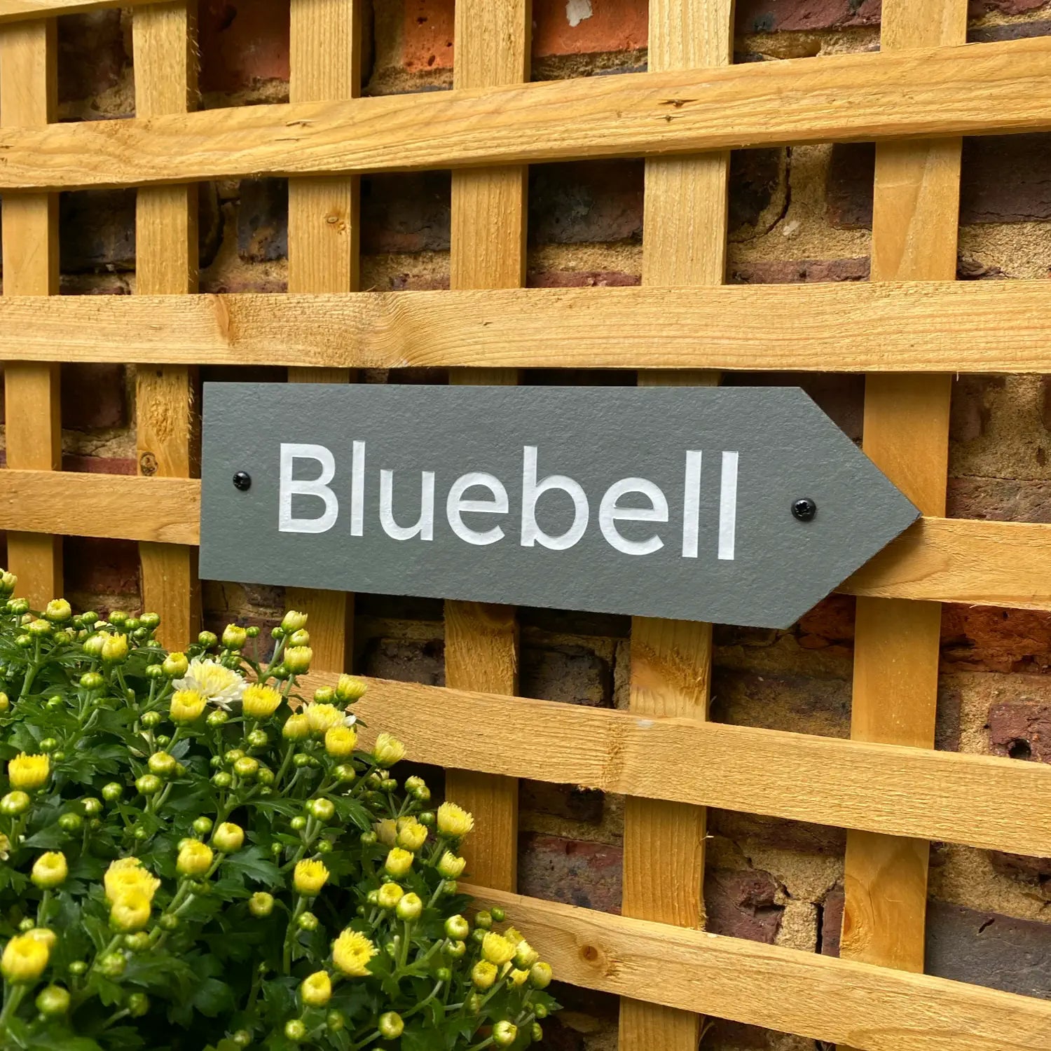a grey slate house sign with a house name and an arrow cut into the right hand side