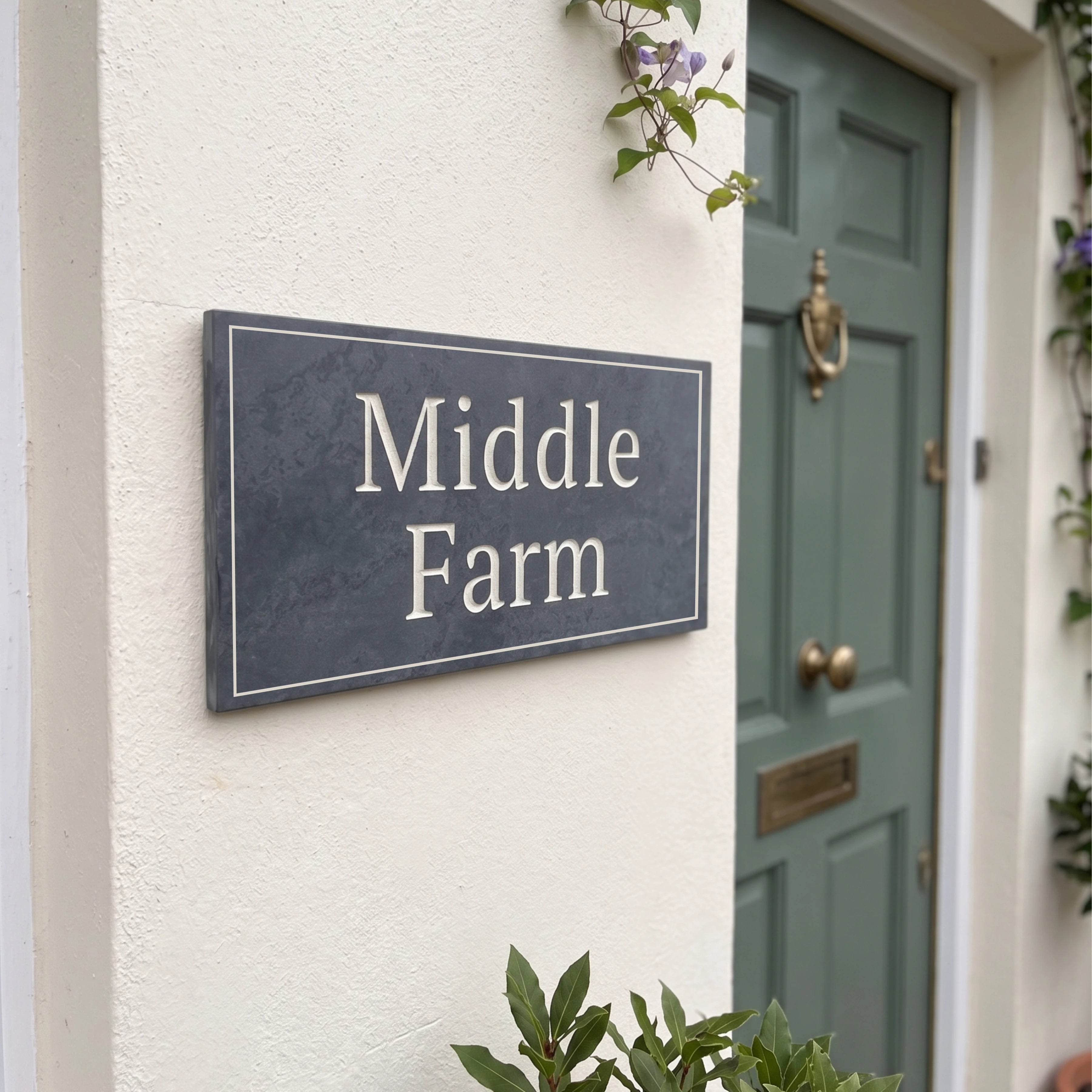 House sign with 'Middle Farm' on a white wall next to a green door.