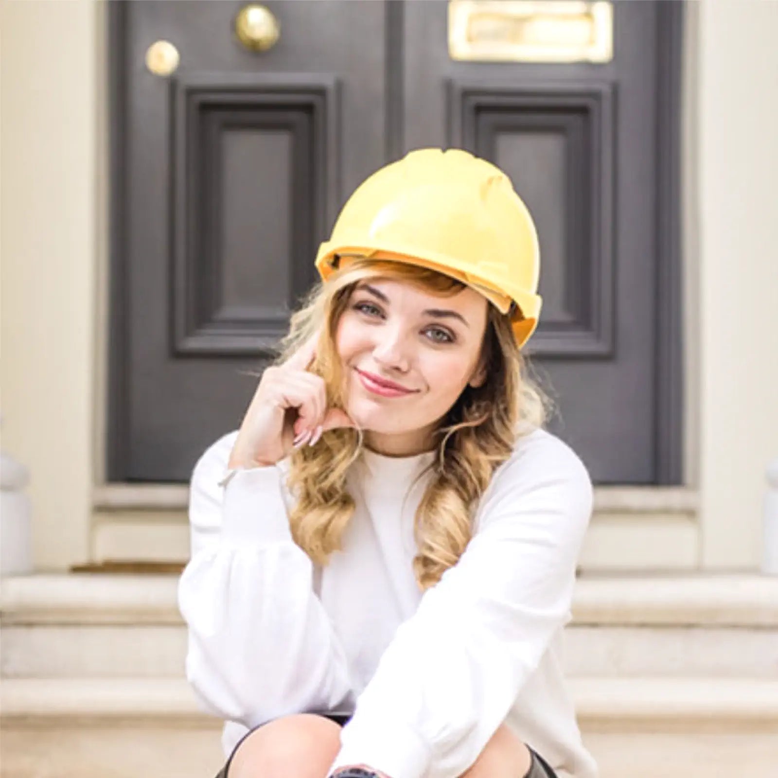 Woman wearing a yellow blazer and white shirt indoors with plants in the background