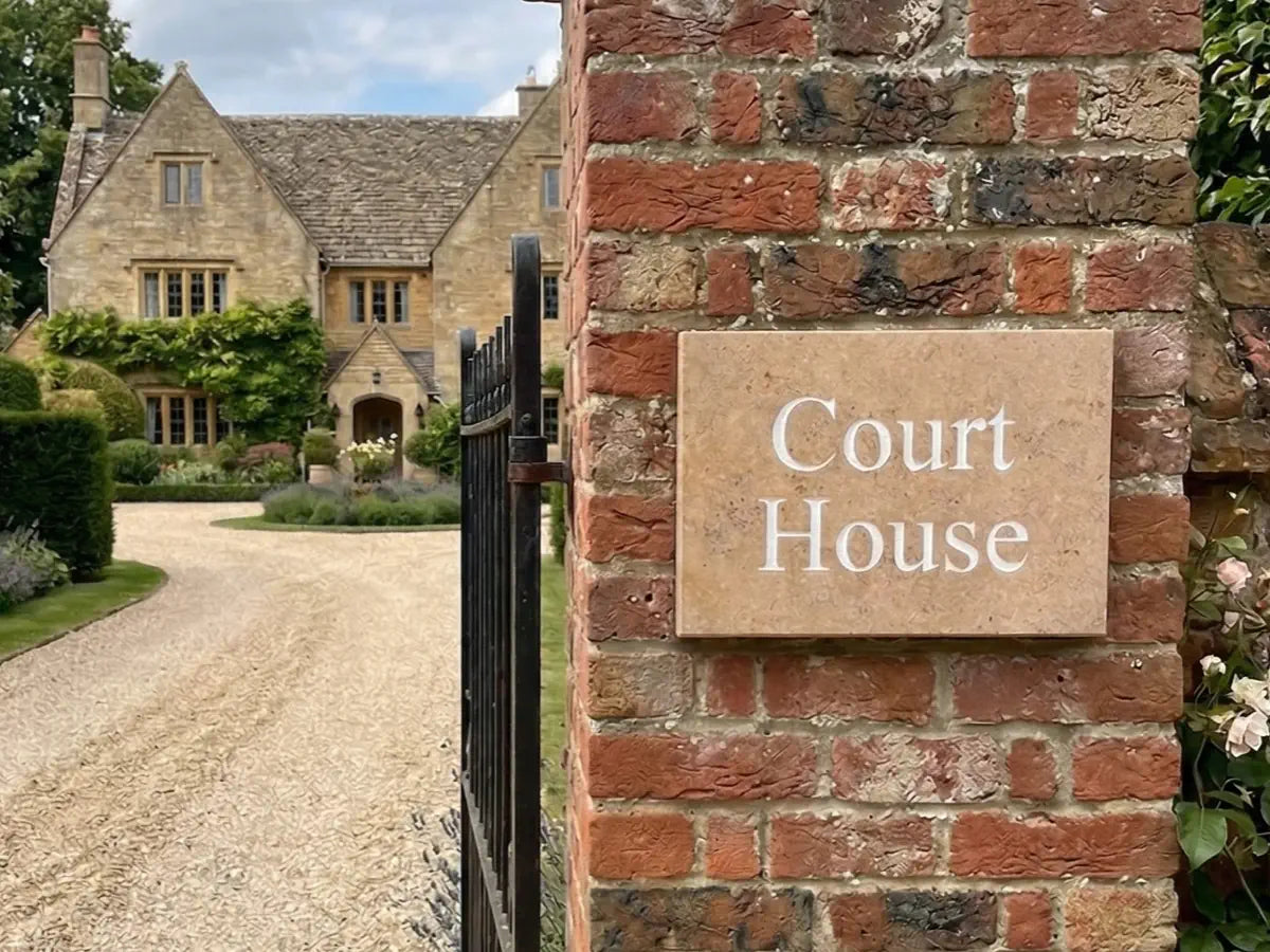 Green door with gold handle and 'Dune View' limestone house sign on a brick wall