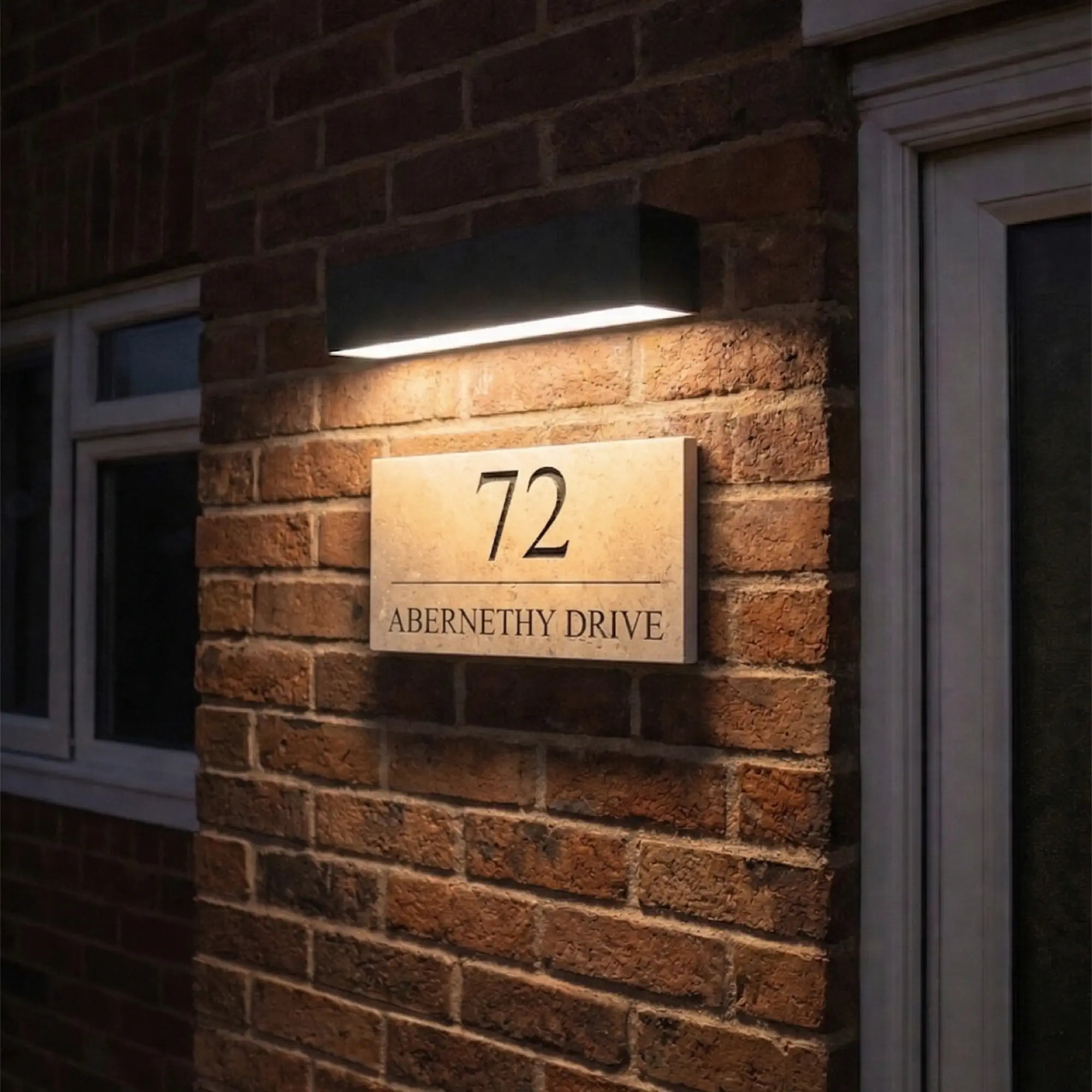 limestone house sign with a turned on solar light above it on a brick wall