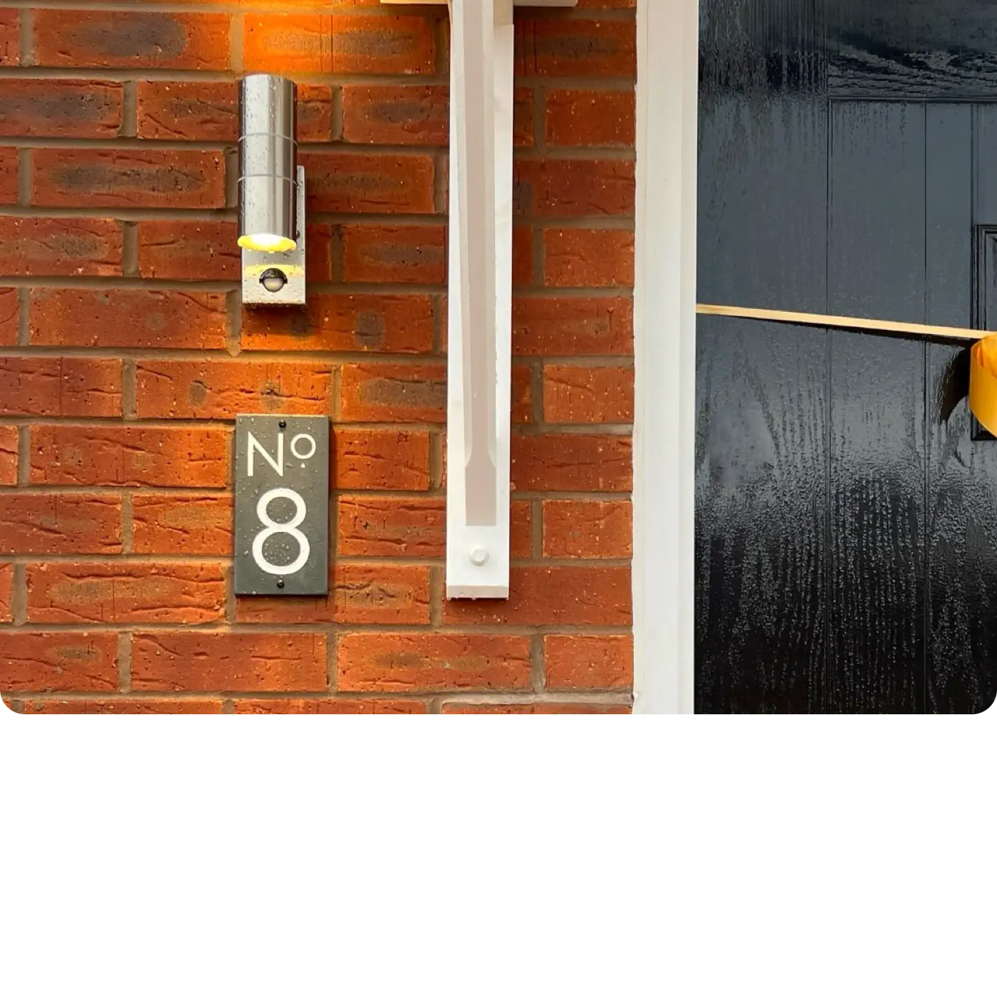 House number 8 on a brick wall with a light fixture above.