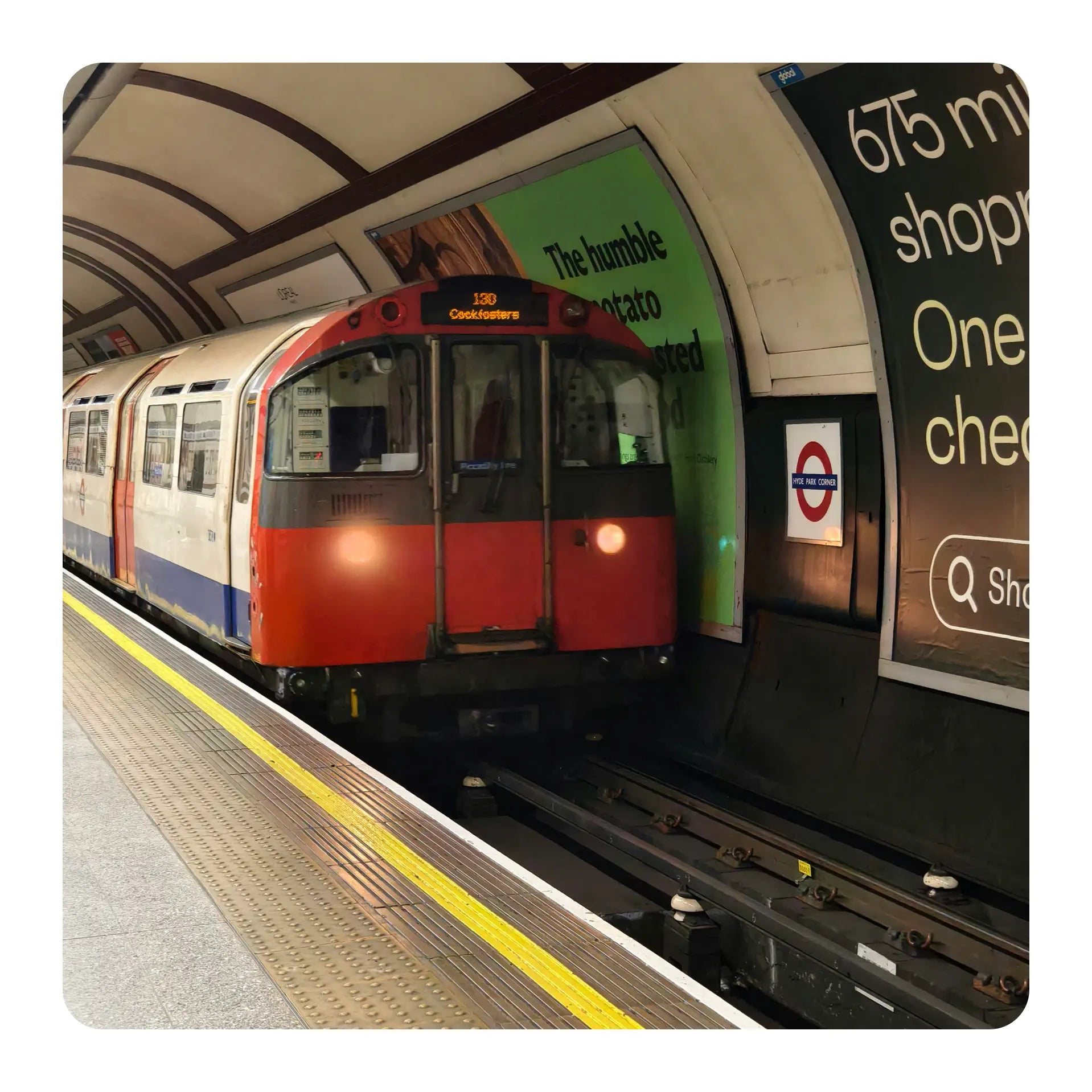 Train arriving at a station with a platform and advertisements in the background