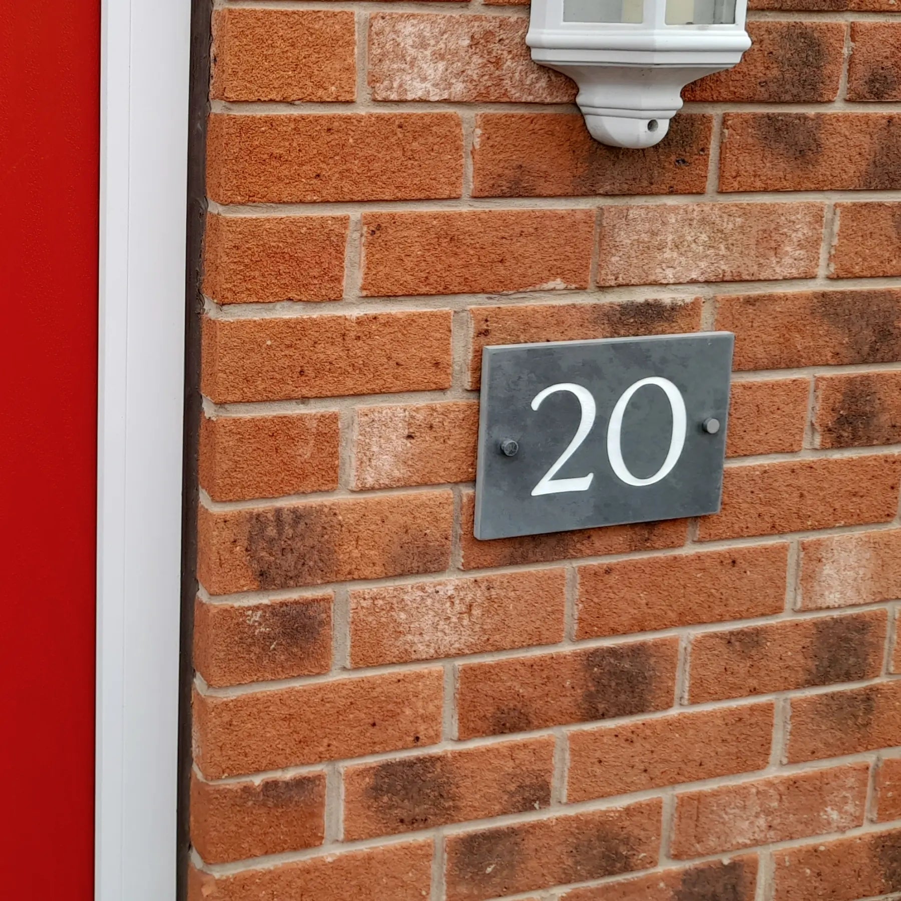 House number '20' on a brick wall with a red door.