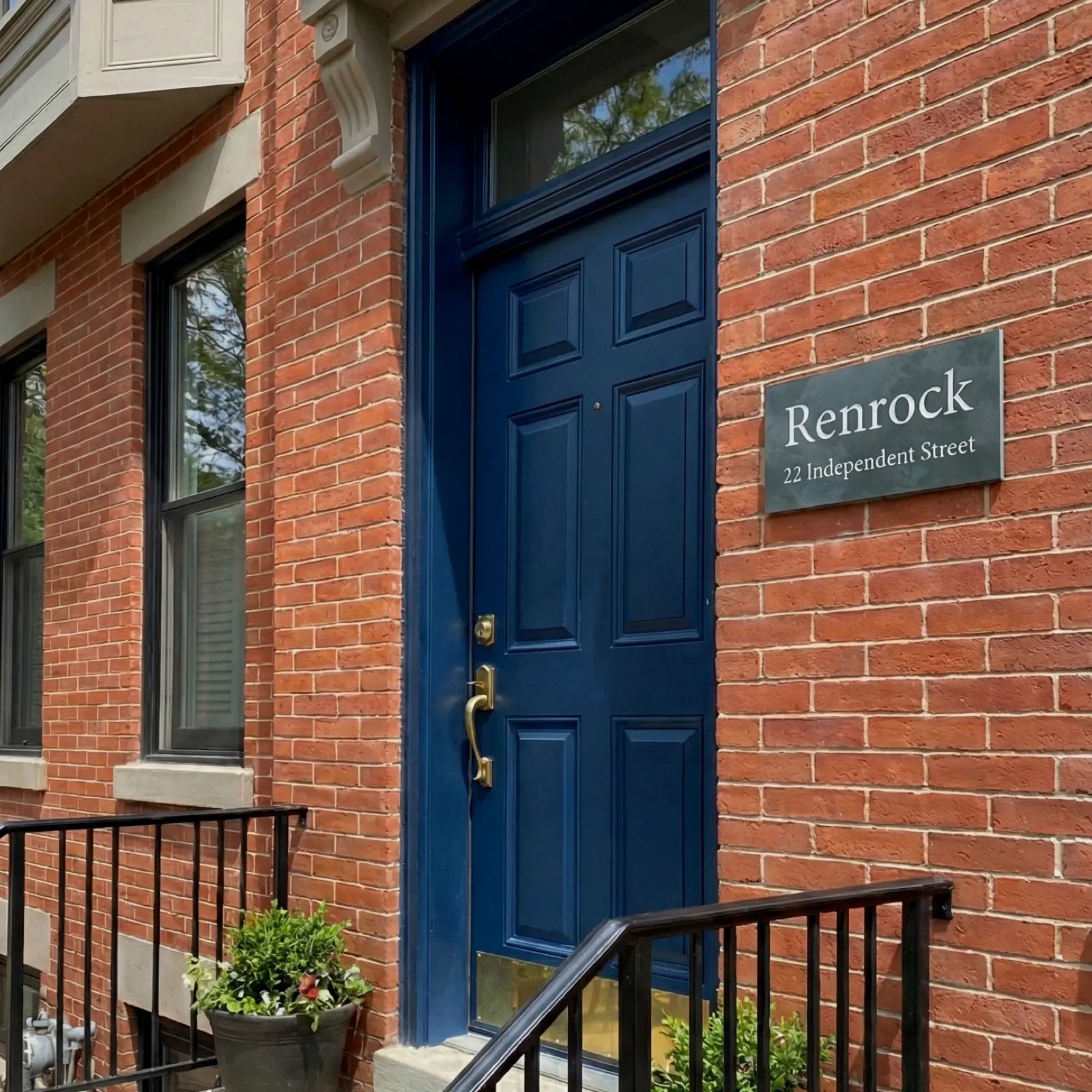 Blue door of a building with 'Renrock' sign on brick wall