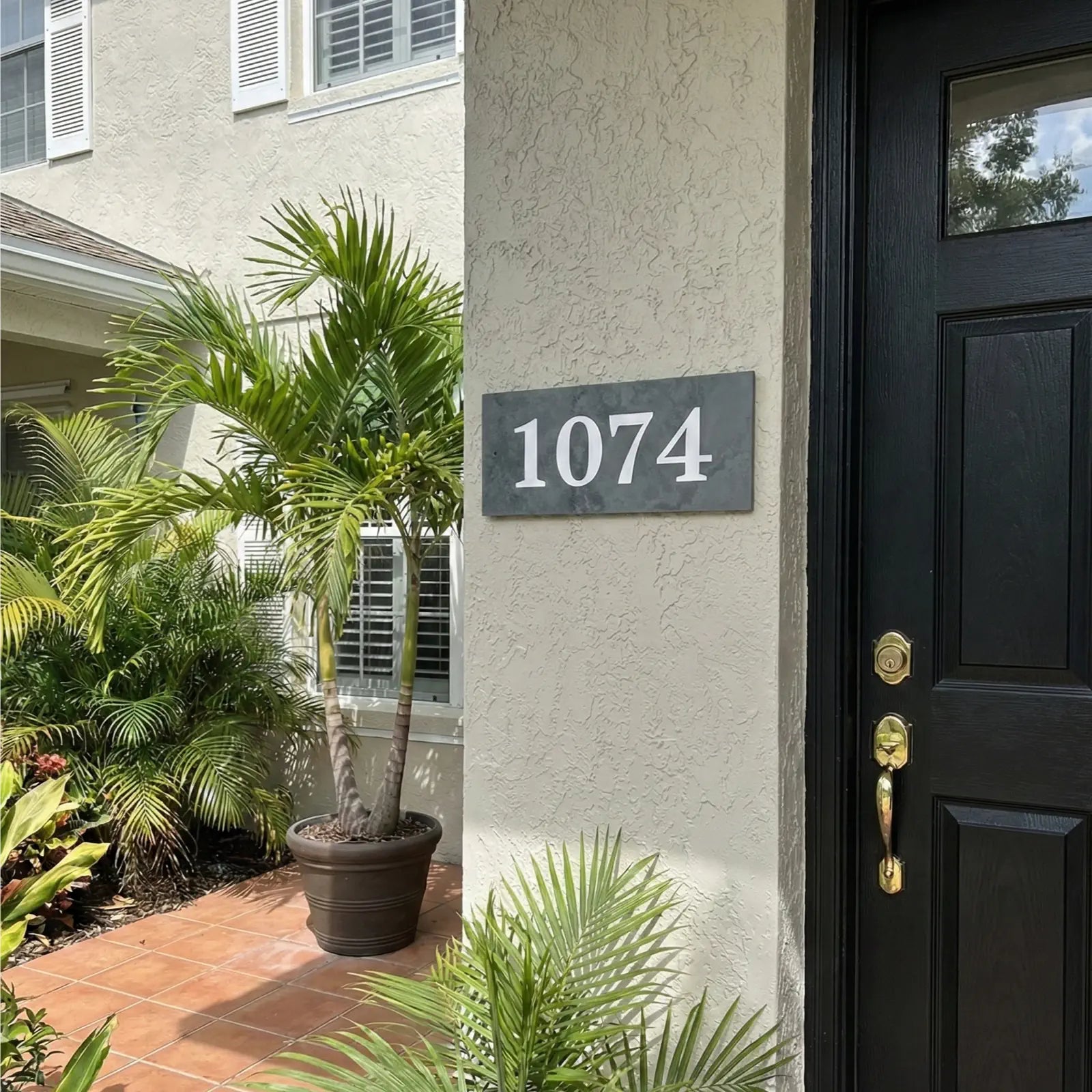 House exterior with a black door, house number 1074, and potted plants.
