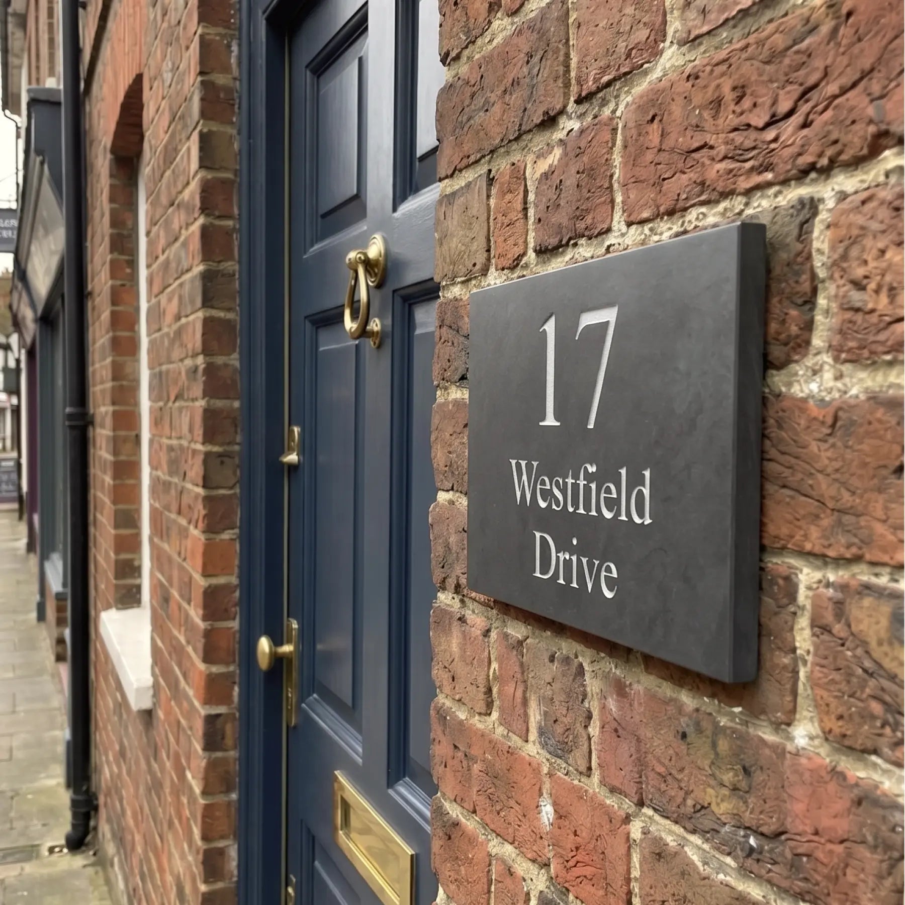 House number 17 Westfield Drive on a brick wall with a blue door.