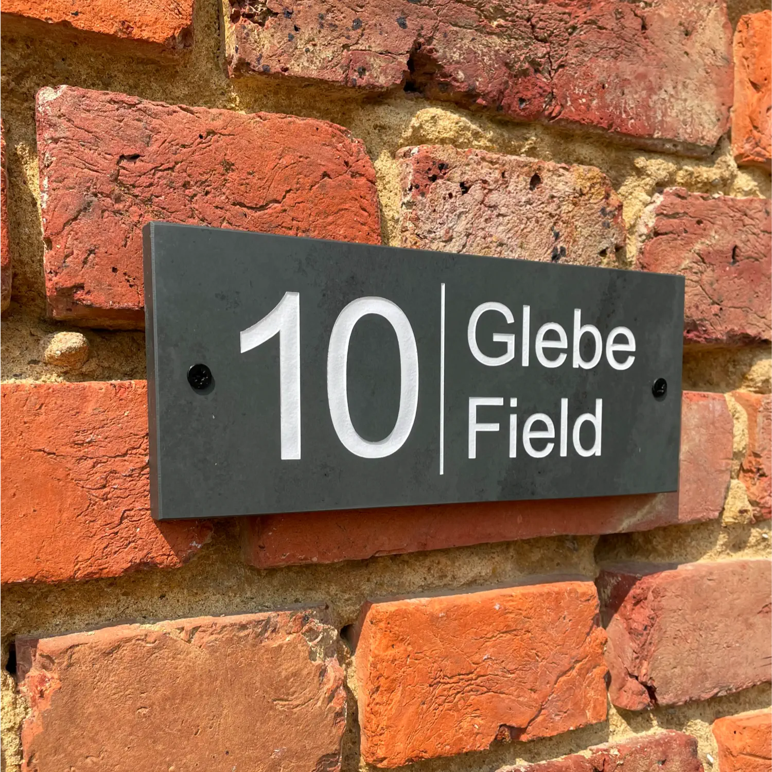 white engraved slate house sign on brick wall