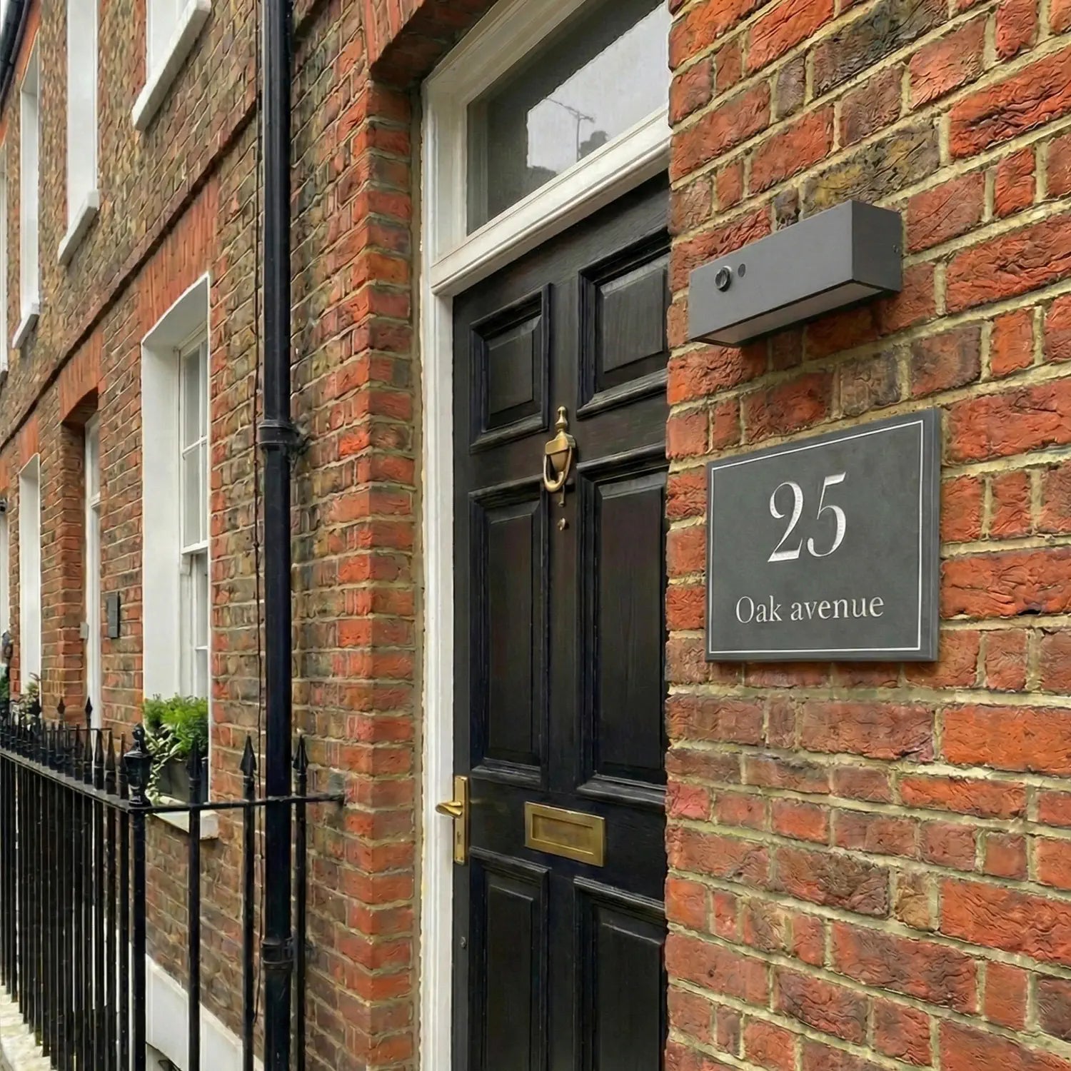 Black door with gold handle and '25 Oak Avenue' sign on a brick building