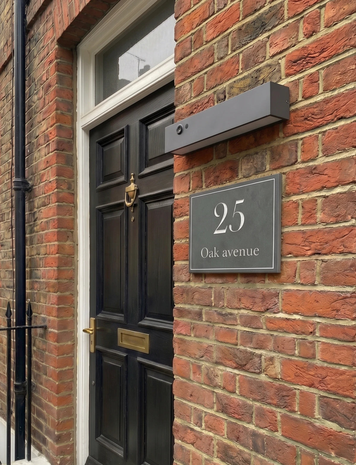 Black door with gold handle and '25 Oak Avenue' sign on a brick building