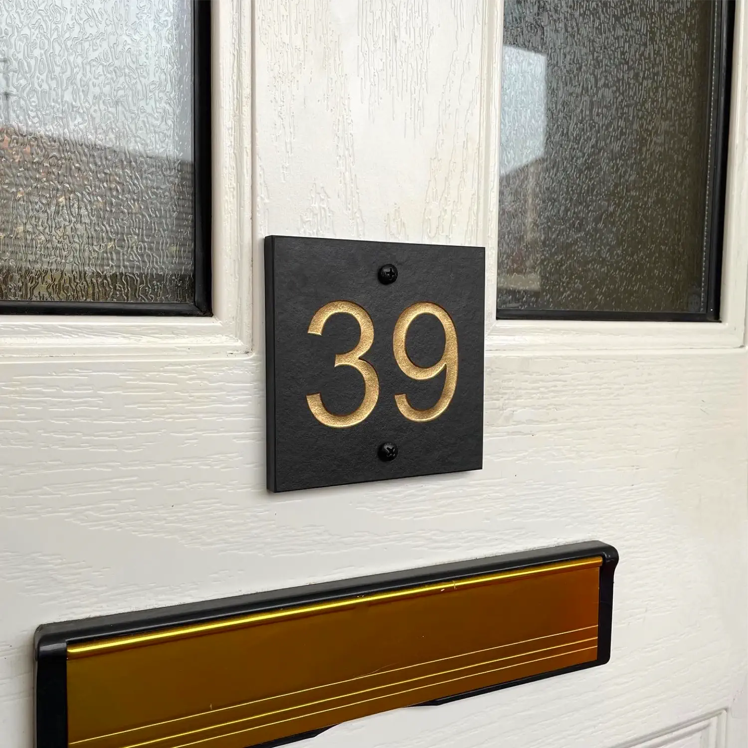 Square gold painted slate sign fixed to a uPVC front door