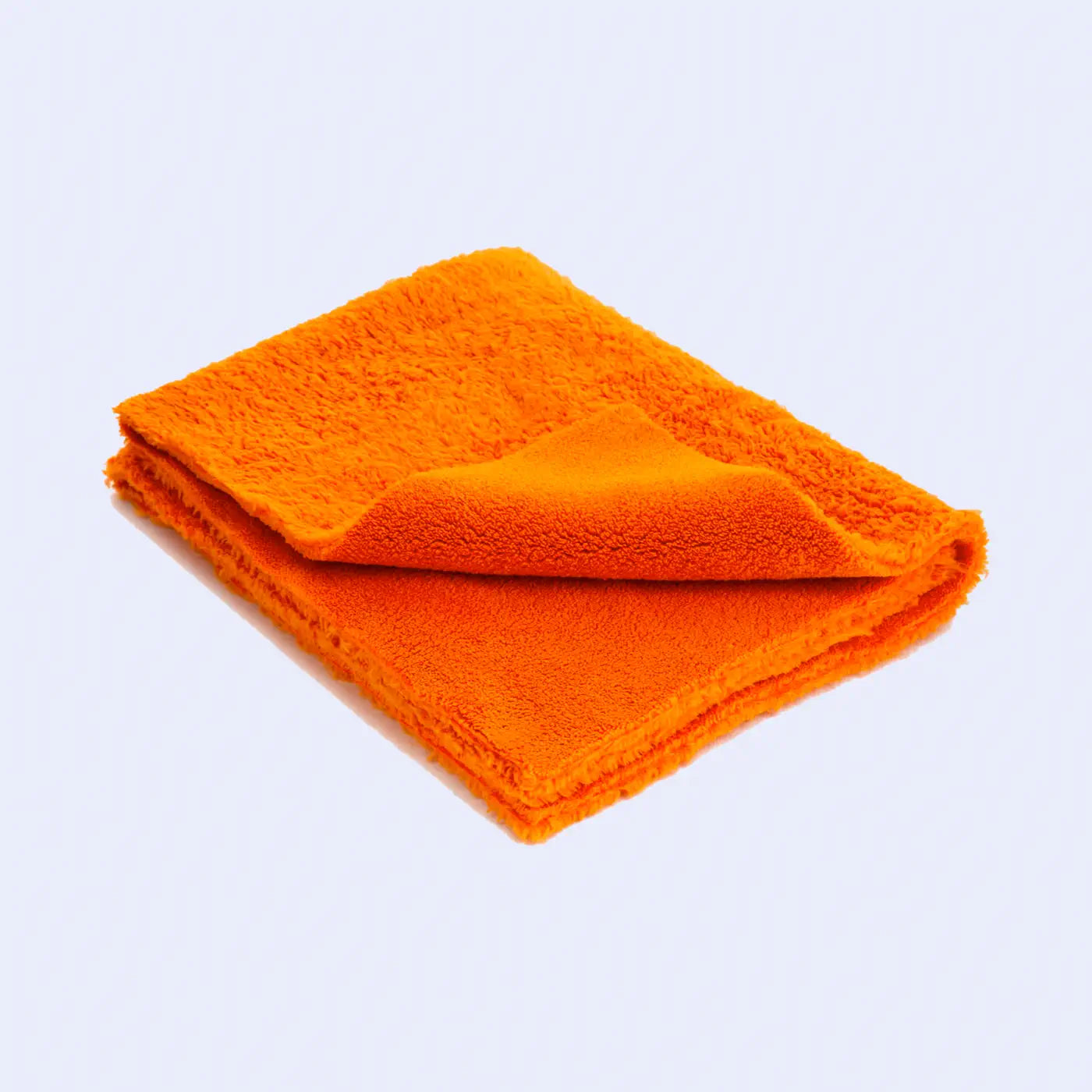 A close-up image of a bottle of slate oil placed on top of a folded, dark-colored microfiber cloth, suggesting the products are used together for cleaning and maintaining slate surfaces.