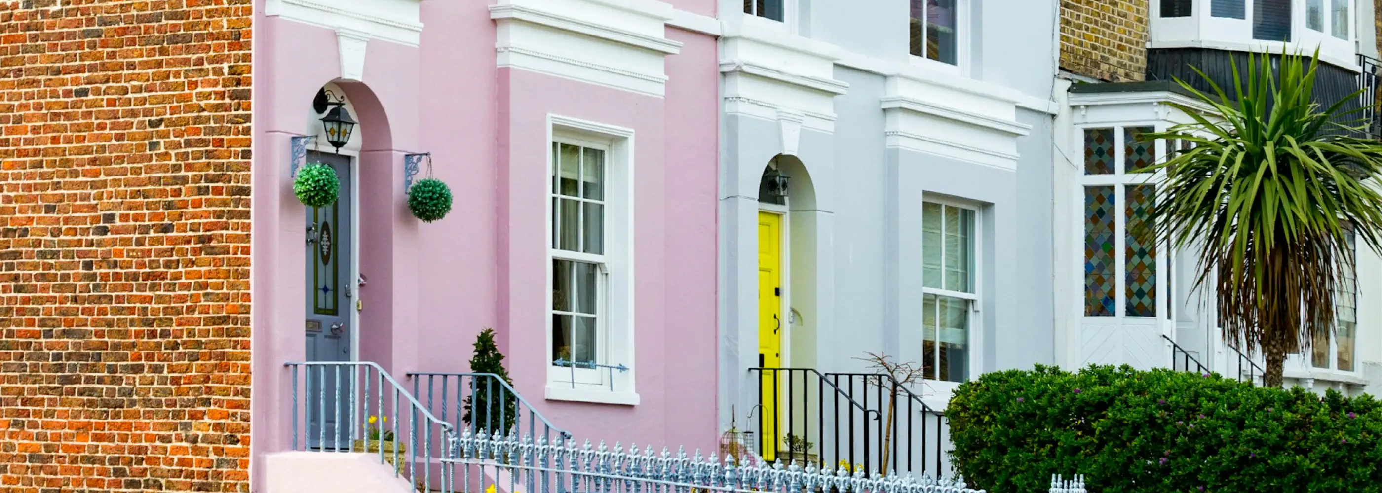 Colorful row of houses with pink, white, and yellow doors in a residential area.