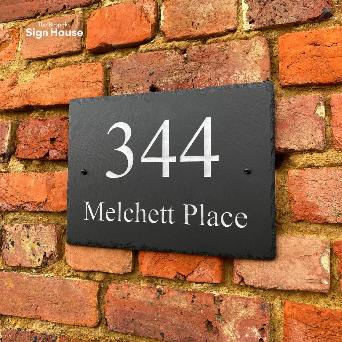 a chiselled welsh slate house sign with house number and name engraved in silver