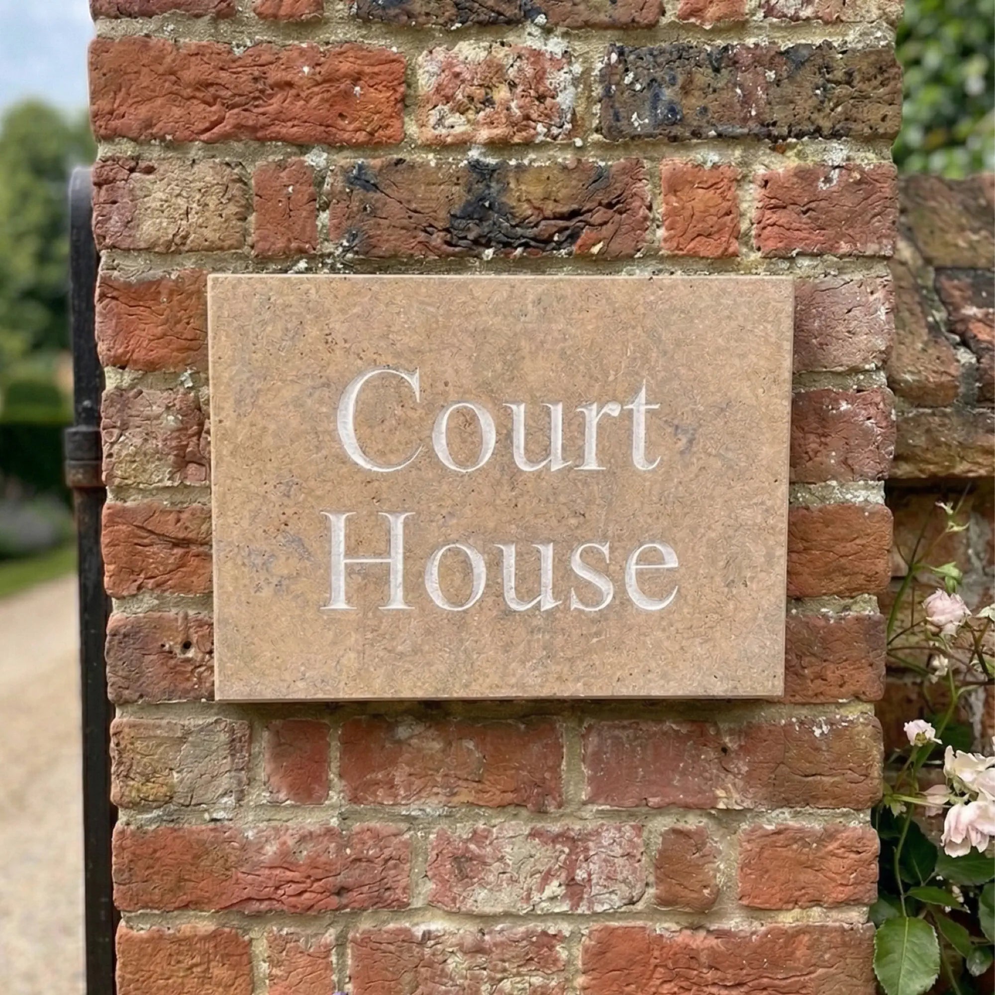 Limestone house sign reading 'Dune View' on a brick wall next to a green door.