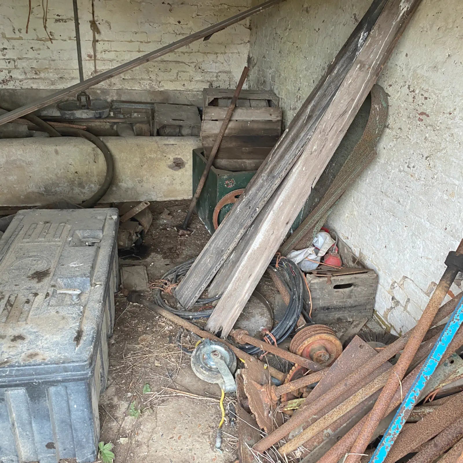 Scattered tools and materials in a cluttered storage area with a concrete wall.