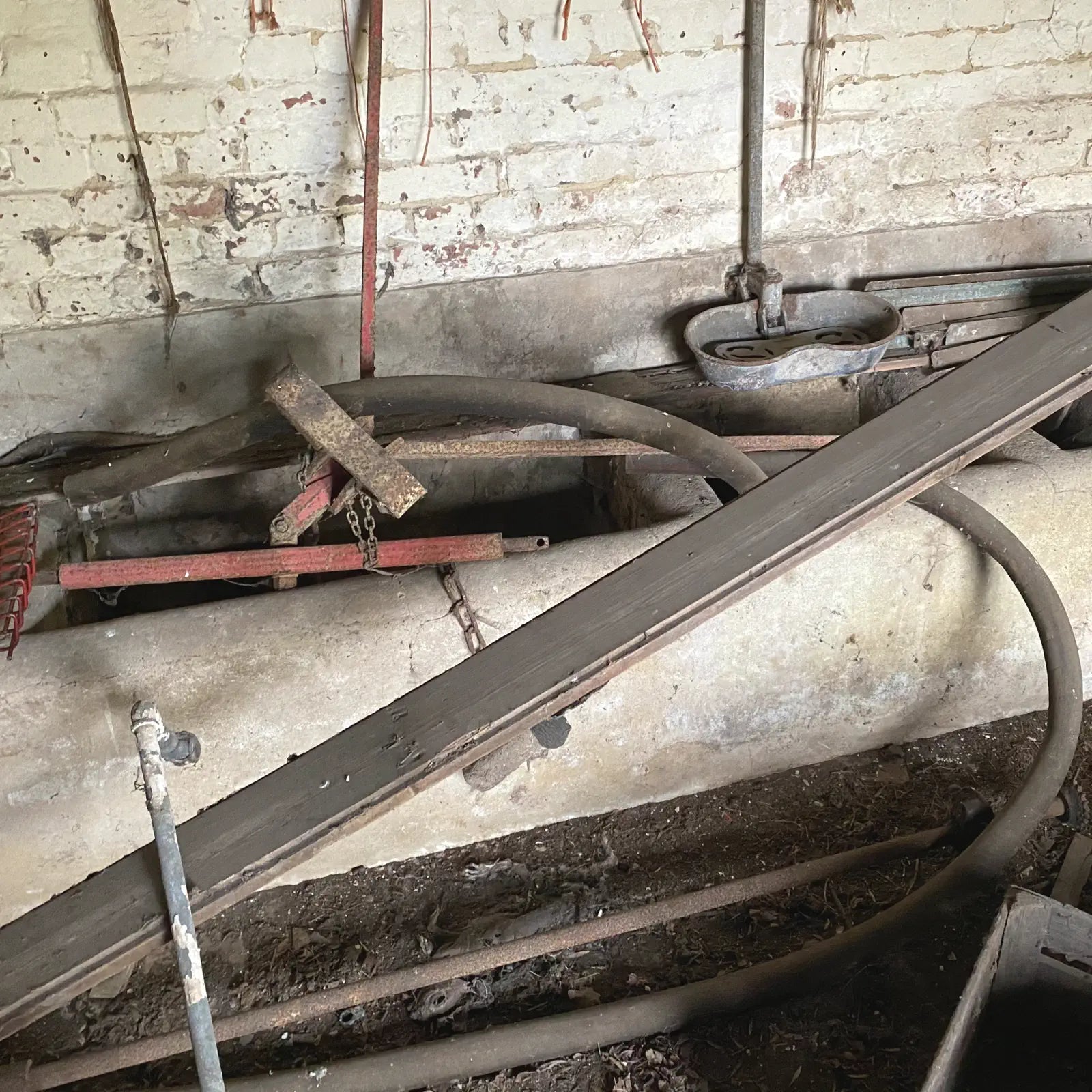 Rusty metal pipes and equipment against a brick wall.