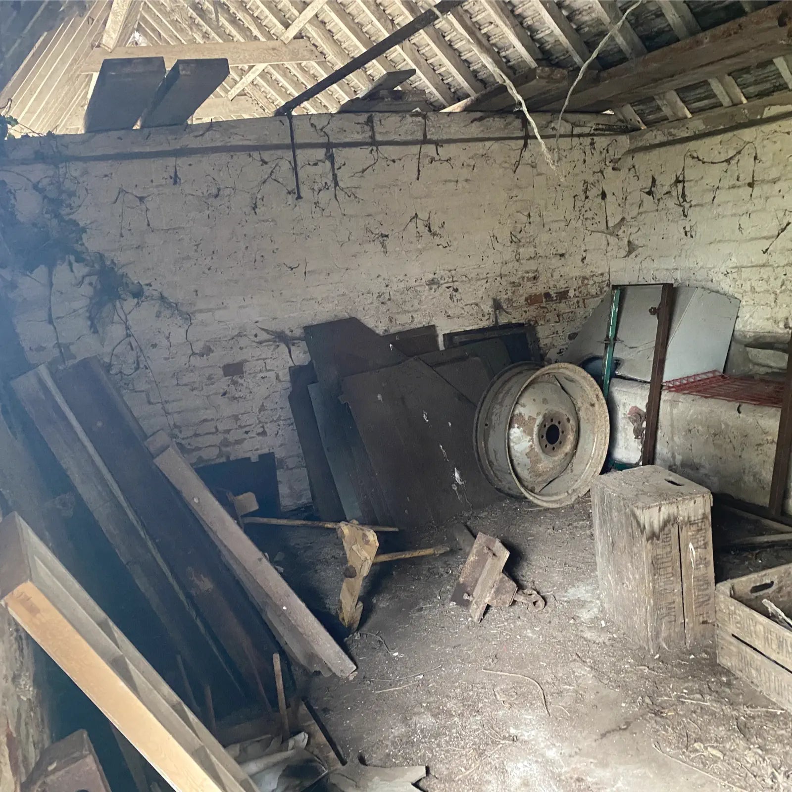 Dilapidated room with debris and old equipment against a brick wall.