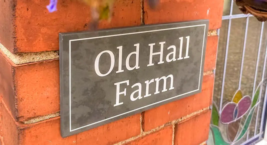 a beautiful grey slate sign on a red brick wall reading old hall farm