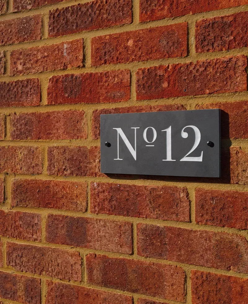 House number plaque 'No. 12' on a brick wall