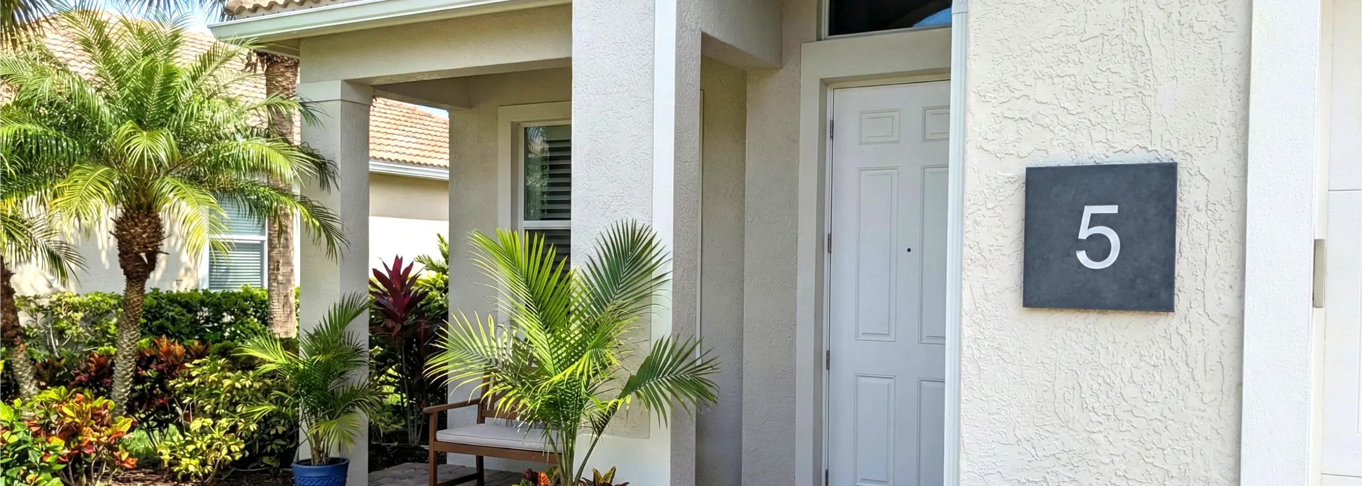 House exterior with a front door number 5 and tropical plants.