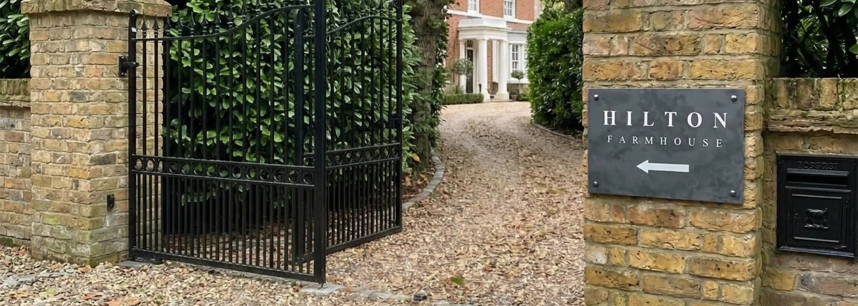 Entrance to Hilton Farmhouse with a black gate and sign.