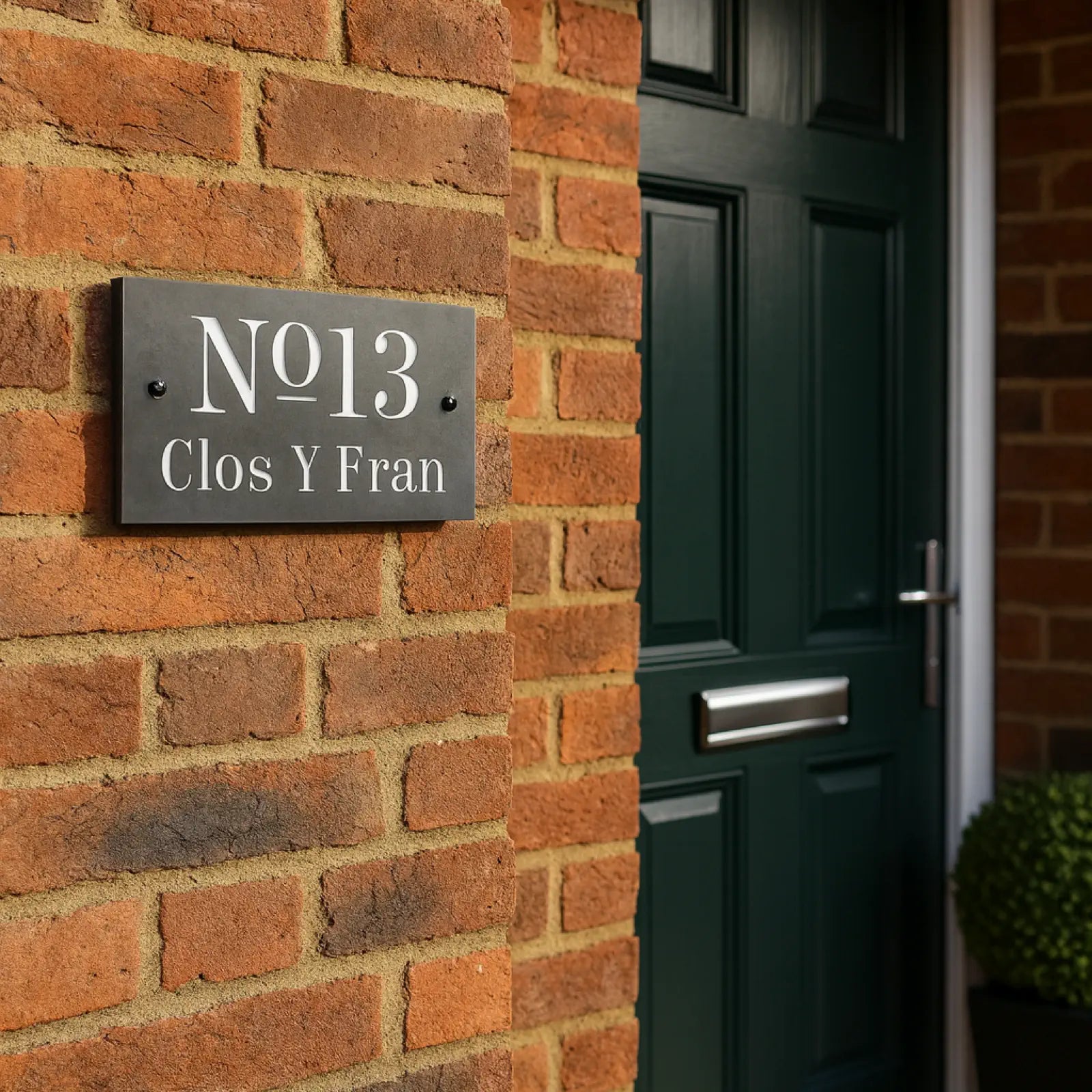 House number sign on a brick wall next to a green door