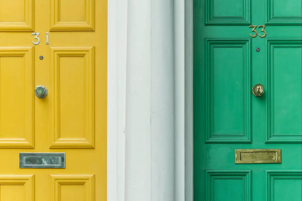 two bright new front doors. One door is yellow with gold numbers saying 31. The door on the right is a light green with gold numbers saying 33